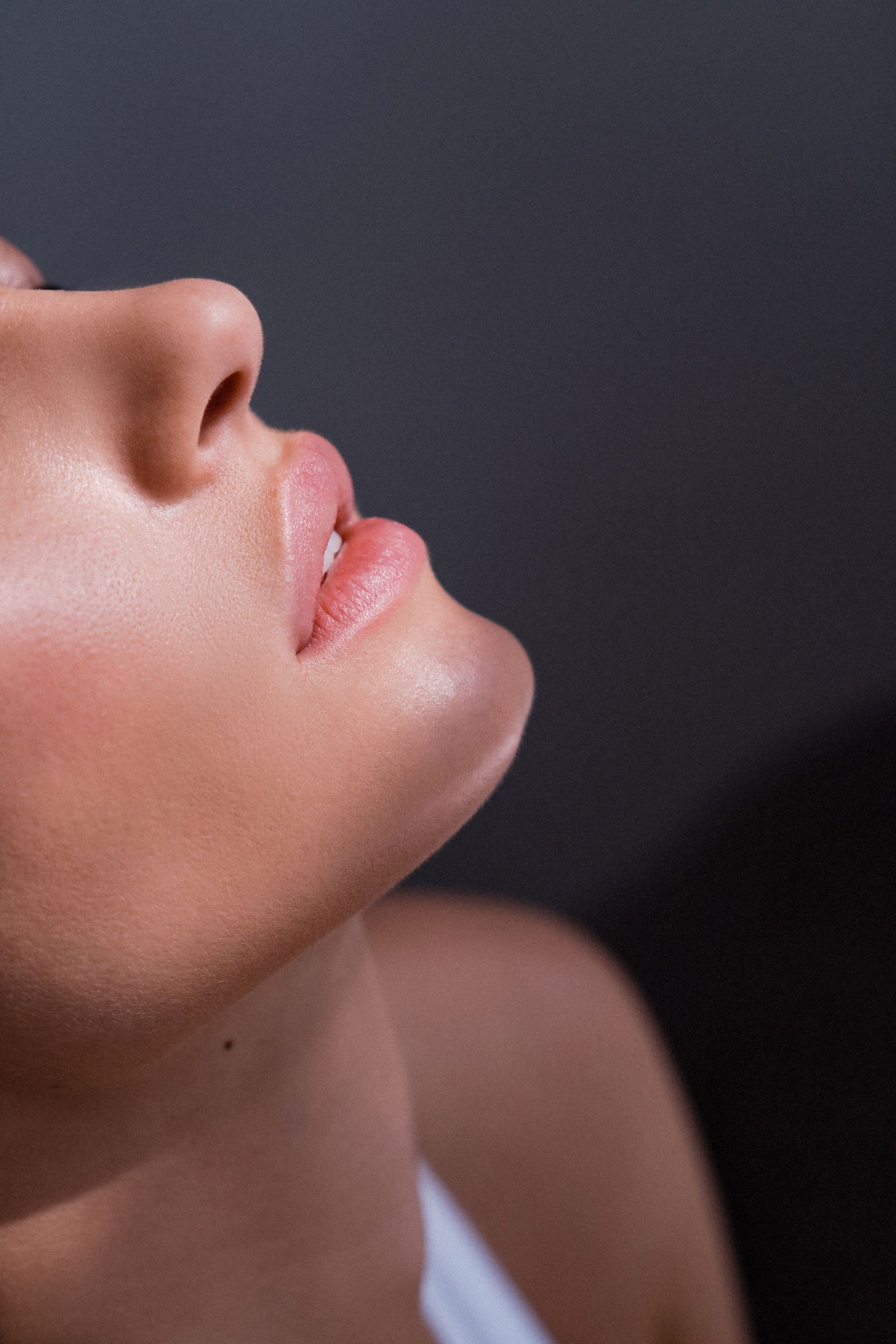Close-up of a person's face showing the nose, lips, and part of the cheek, with a dark background.