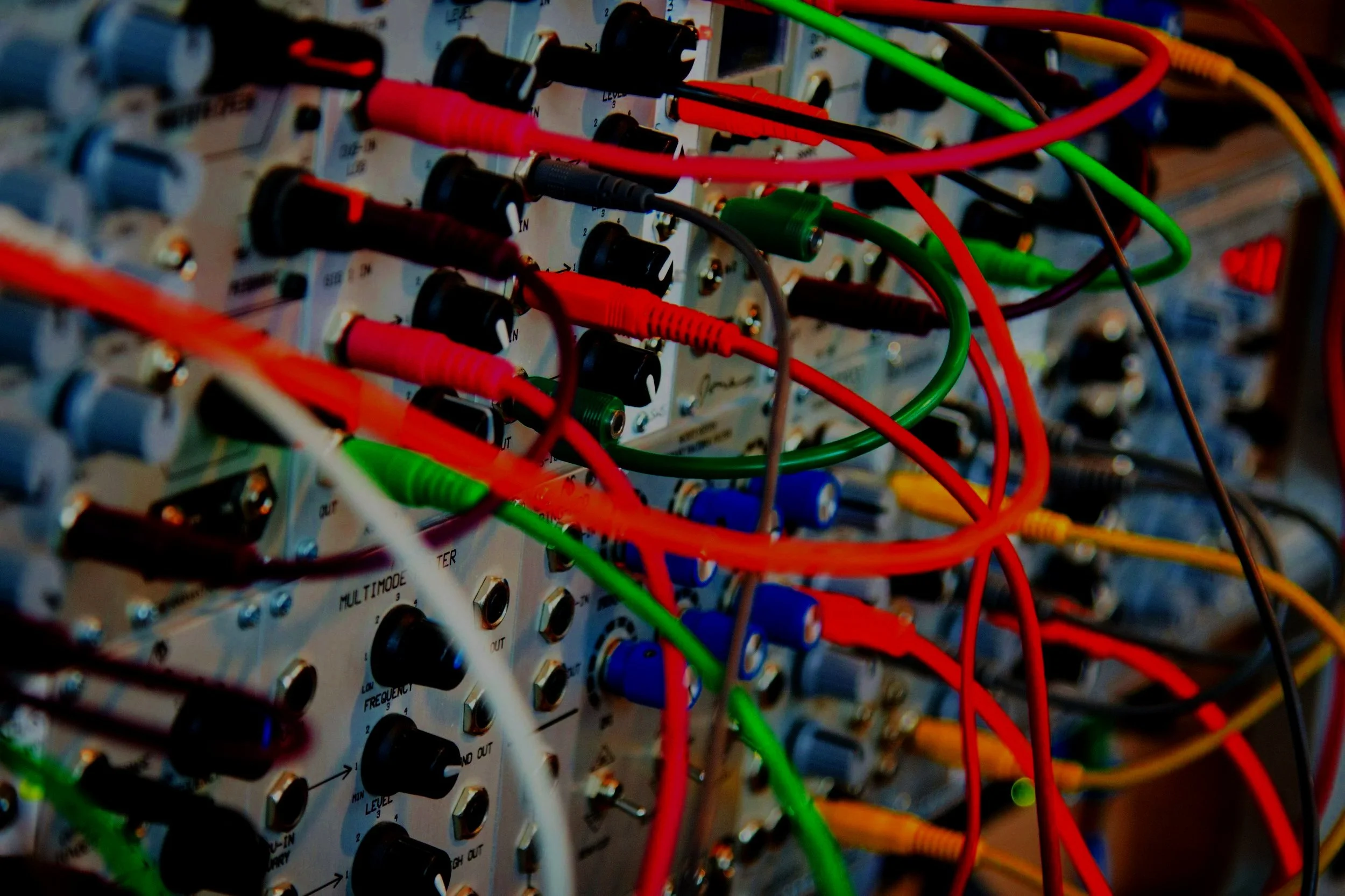 Close-up of an electronics circuit board with multicolored wires connected to various ports and controls.