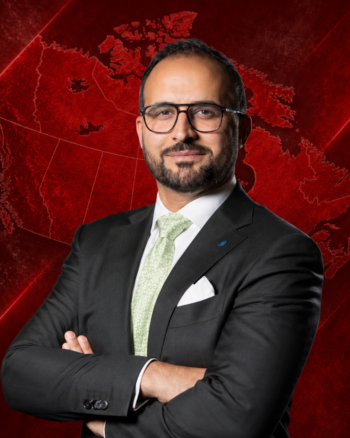 Professional man wearing glasses and a suit, standing with arms crossed against a plain background.