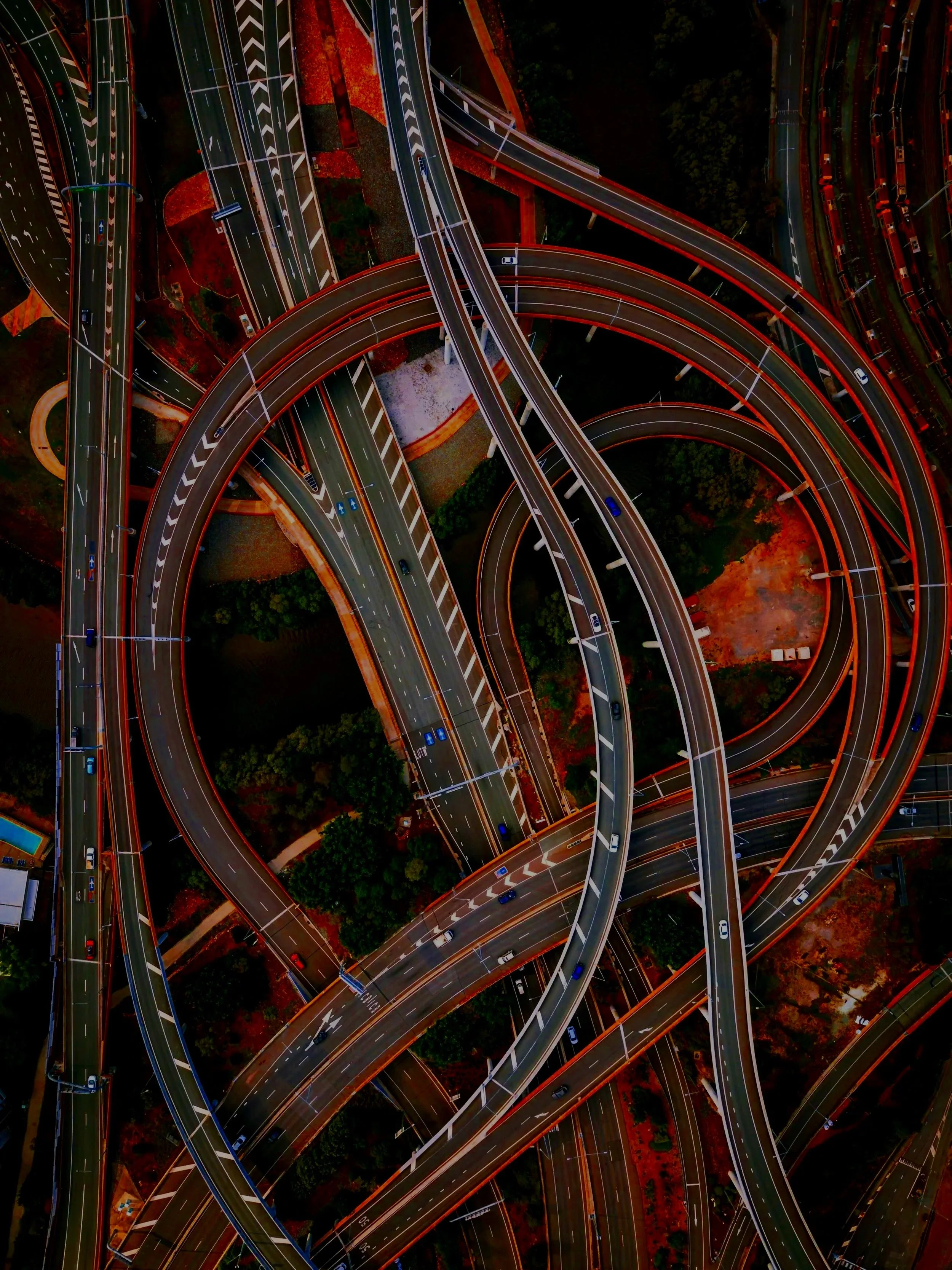 Aerial view of an intricate network of highway overpasses and ramps illuminated at night, with cars visible on the roads.