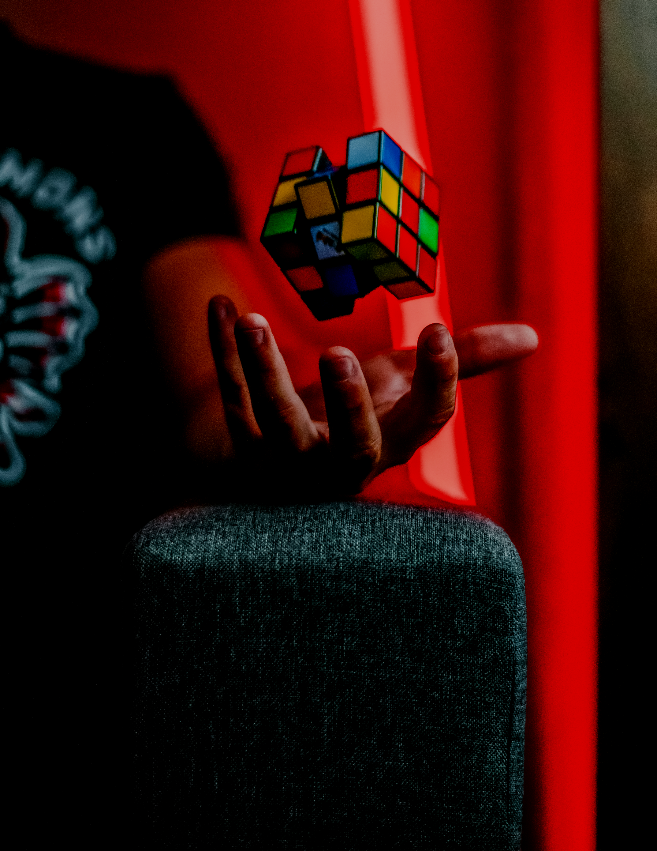 Person wearing a red shirt holding a Rubik's cube against a red background.