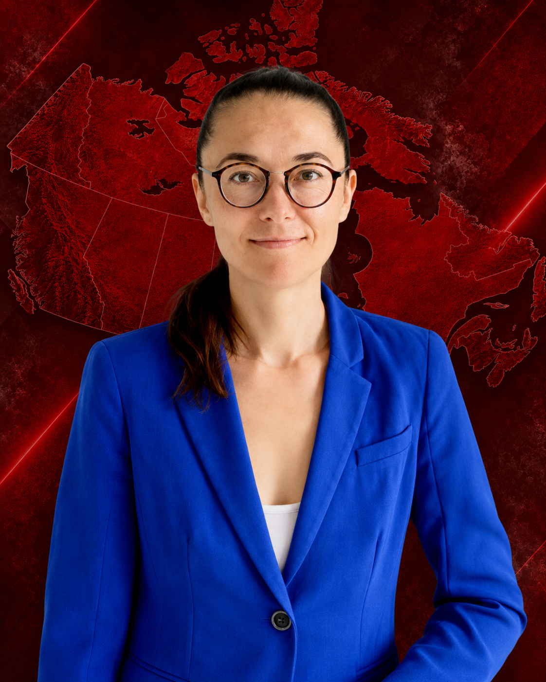 A woman with glasses and a ponytail wearing a blue blazer and white top, standing against a plain light background.