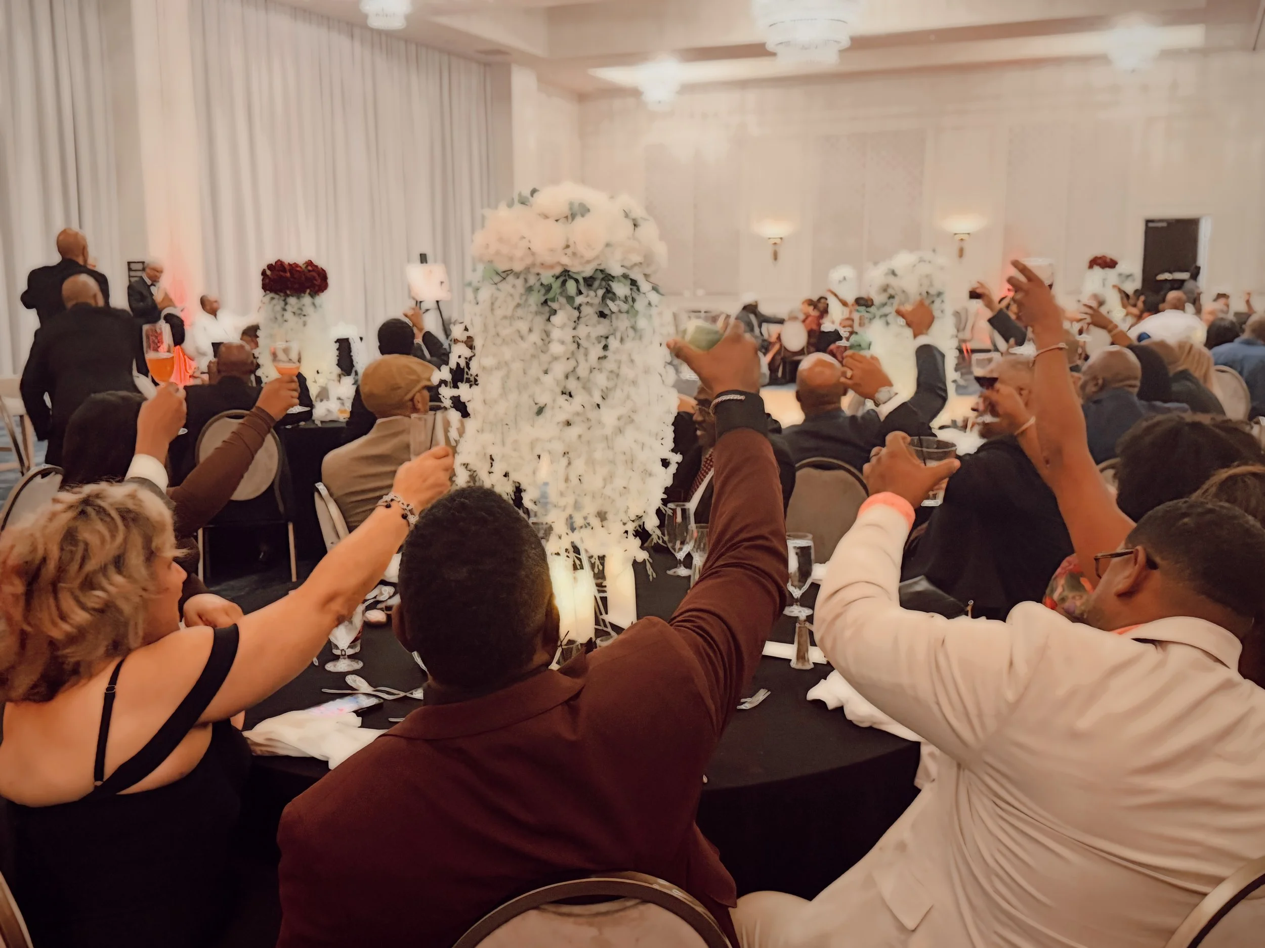 Guests raise their glasses for a toast at an elegantly decorated wedding reception in a ballroom at the Hutton Hotel in Nashville, Tennessee.
