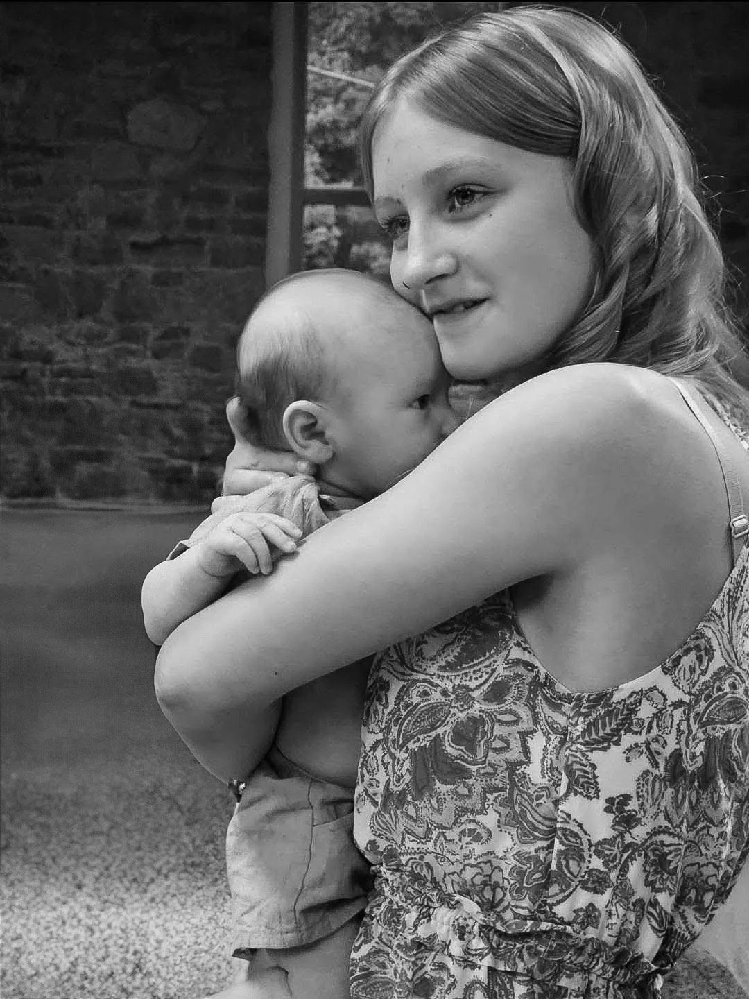 A bridesmaid smiles as she holds a baby to her chest at a wedding in New Castle, Indiana.