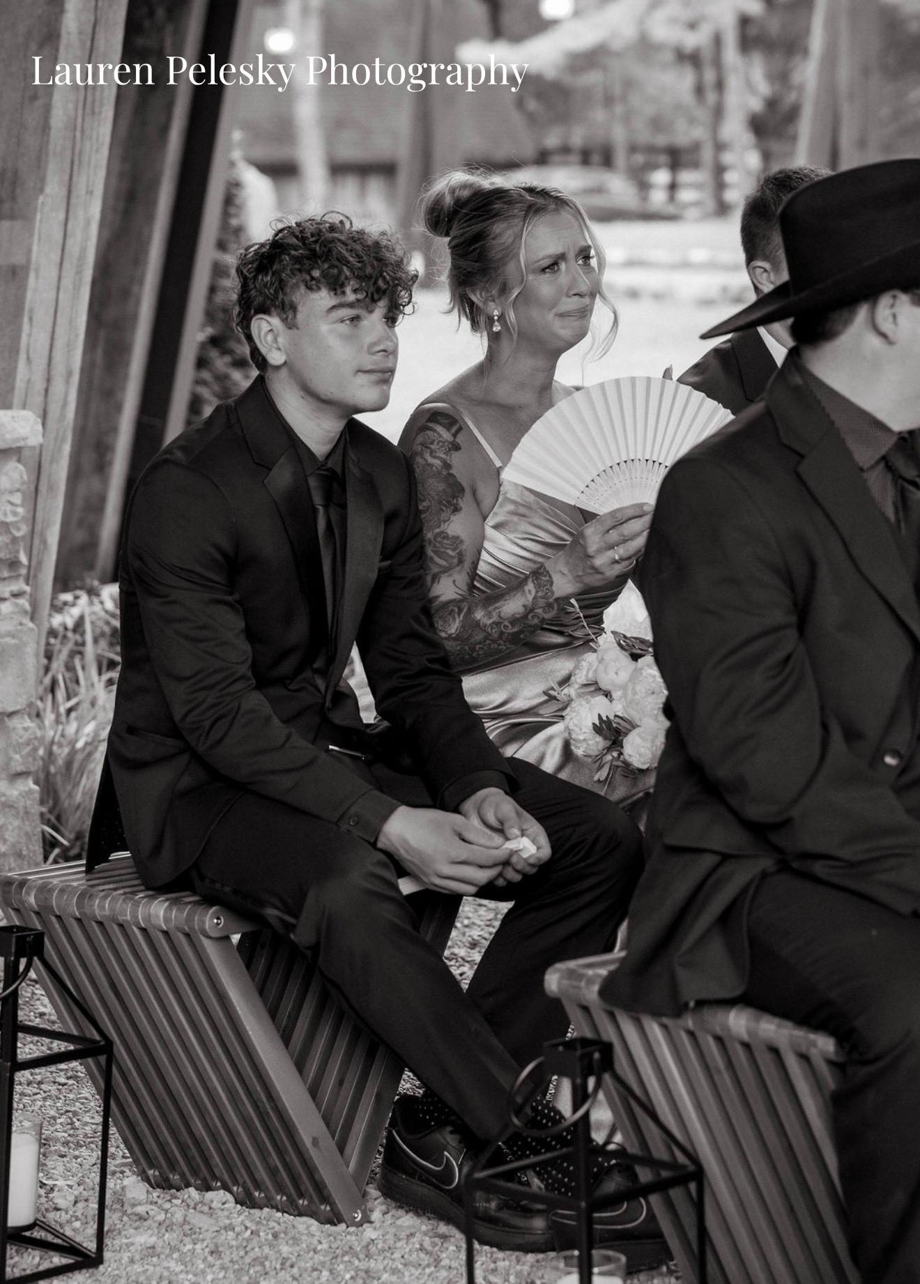 A bridesmaid seated next to her son waves a fan as she cries during a wedding ceremony in Franklin, Tennessee.