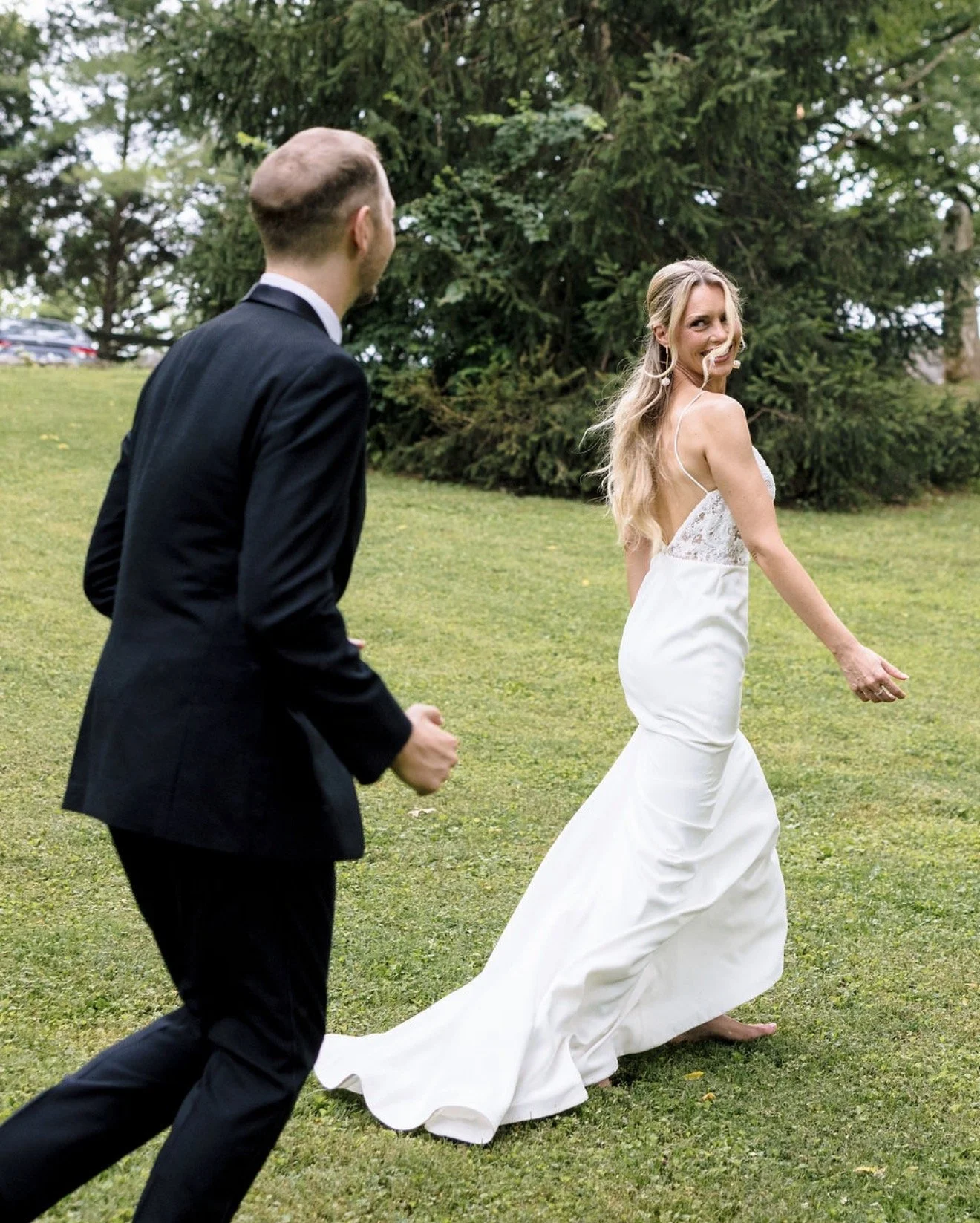 A bride in a white wedding dress smiles back as her groom playfully chases her at a wedding in Franklin, Tennessee.