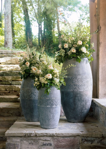 White rose floral arrangements sit in large gray stone vases beside a wedding altar at a wedding in Franklin, Tennessee, coordinated by Vow & Valley Wedding Co.