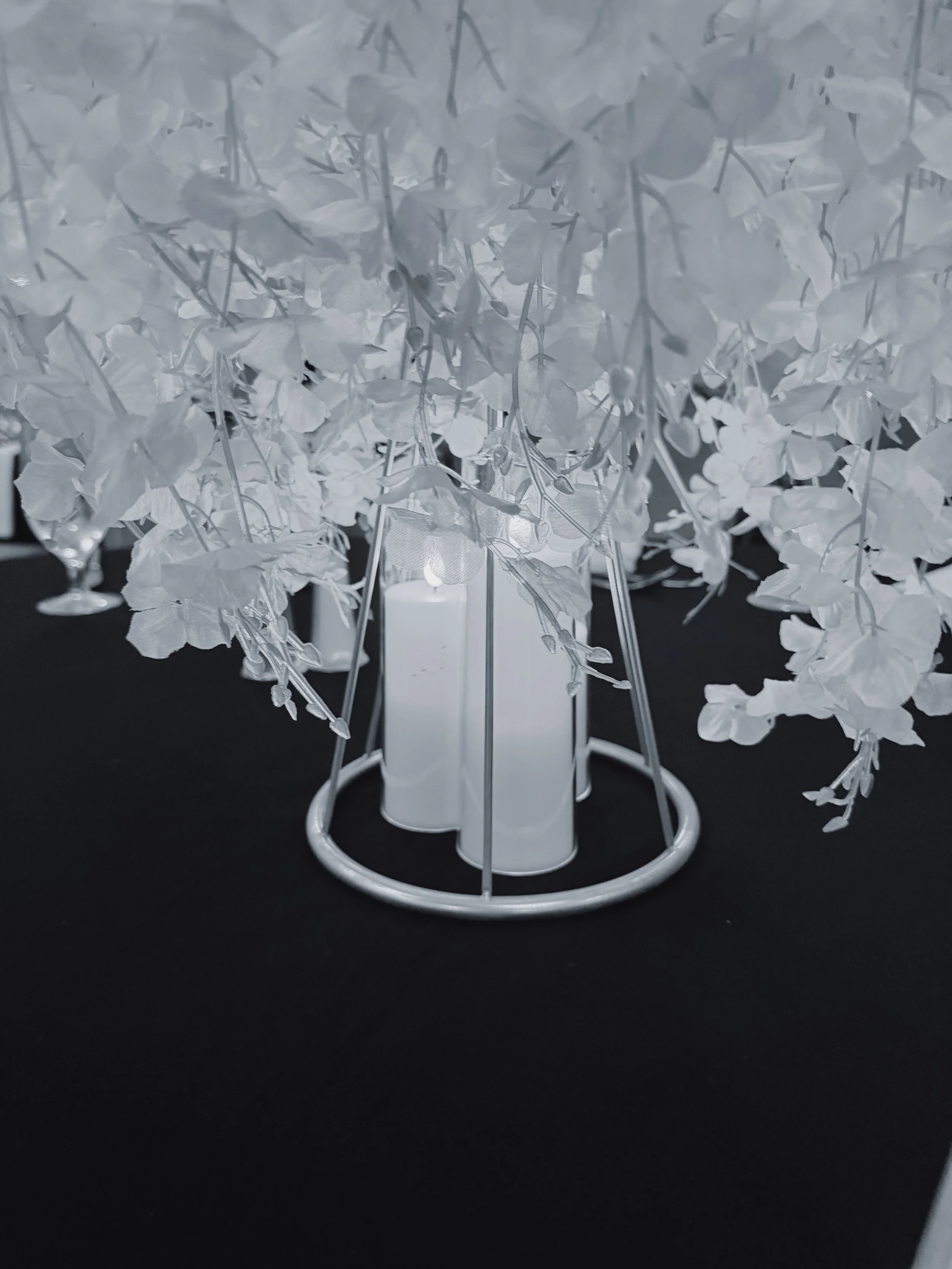 White hanging florals drape over LED candles placed atop a black tablecloth as a centerpiece at a wedding reception in Nashville, Tennessee.