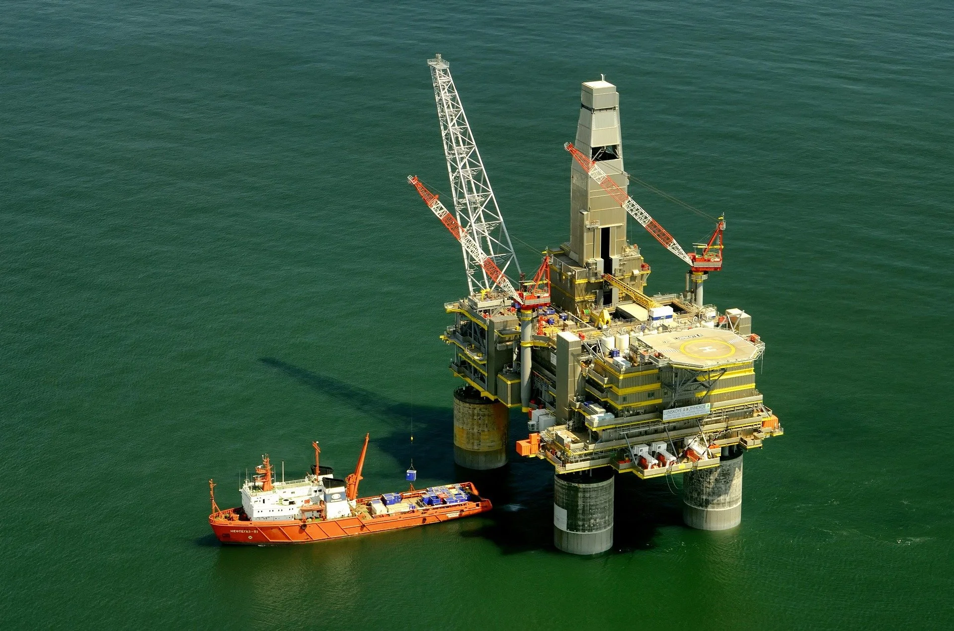 An offshore oil drilling rig in the ocean with a supply boat nearby.