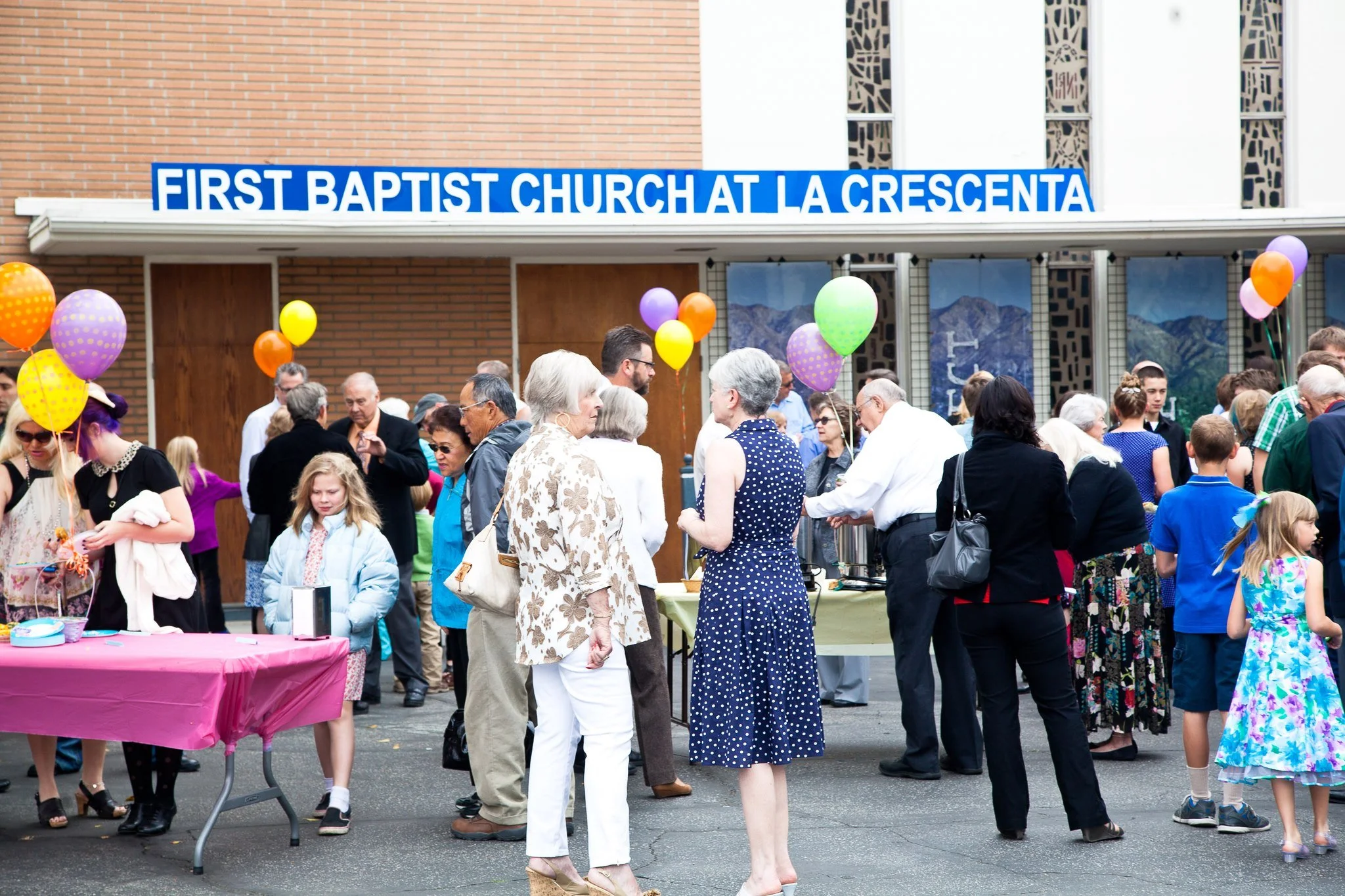People gathered outside a church decorated with balloons for an event.