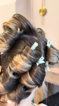 Person's hair is in rollers with hair clips, preparing for a hairstyle.