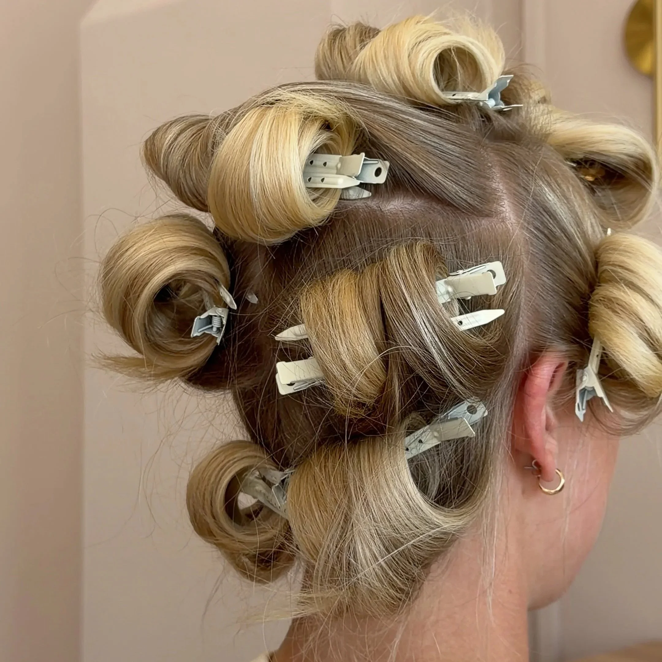 Hair rollers and clips in blonde hair, preparing for styling or setting hair.