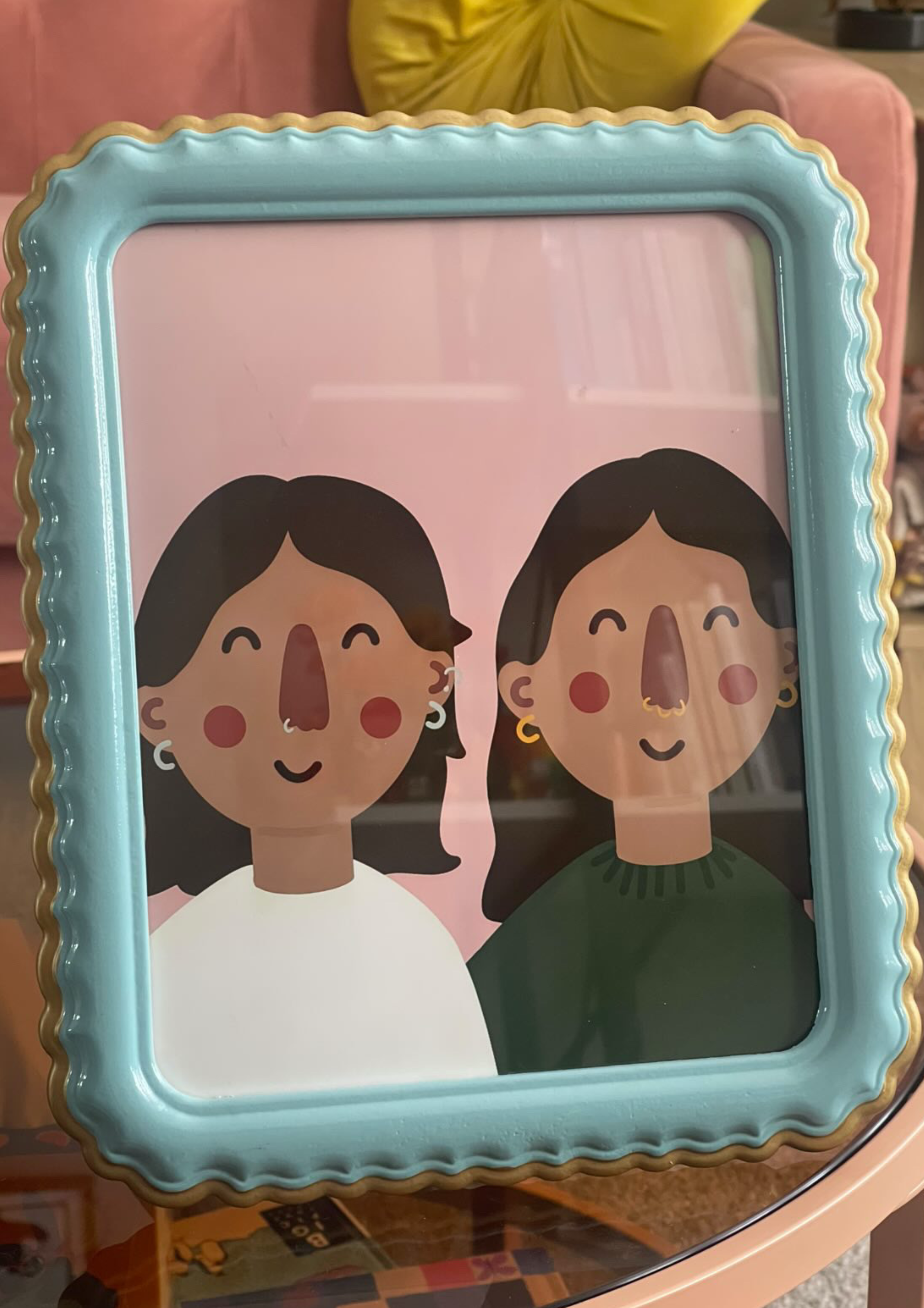 Decorative tray with two illustrated women with dark hair, one with a white shirt and the other with a green shirt. The tray has a wavy blue border with a gold edge.