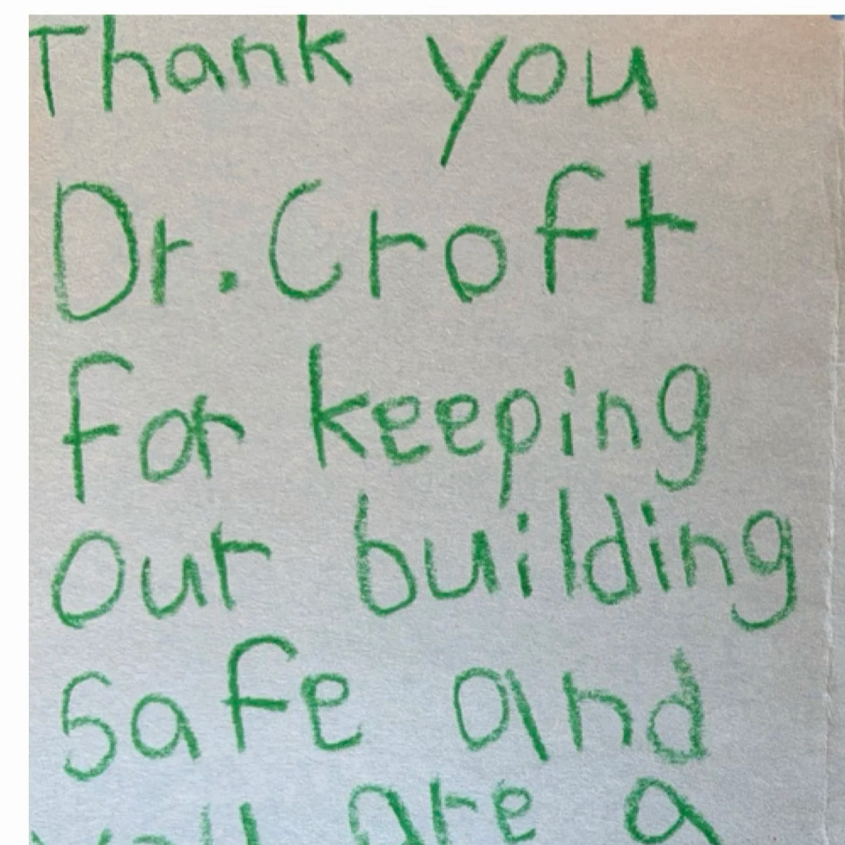 Handwritten note in green ink on white paper that says, 'Thank you Dr. Croft for keeping our building safe and'.