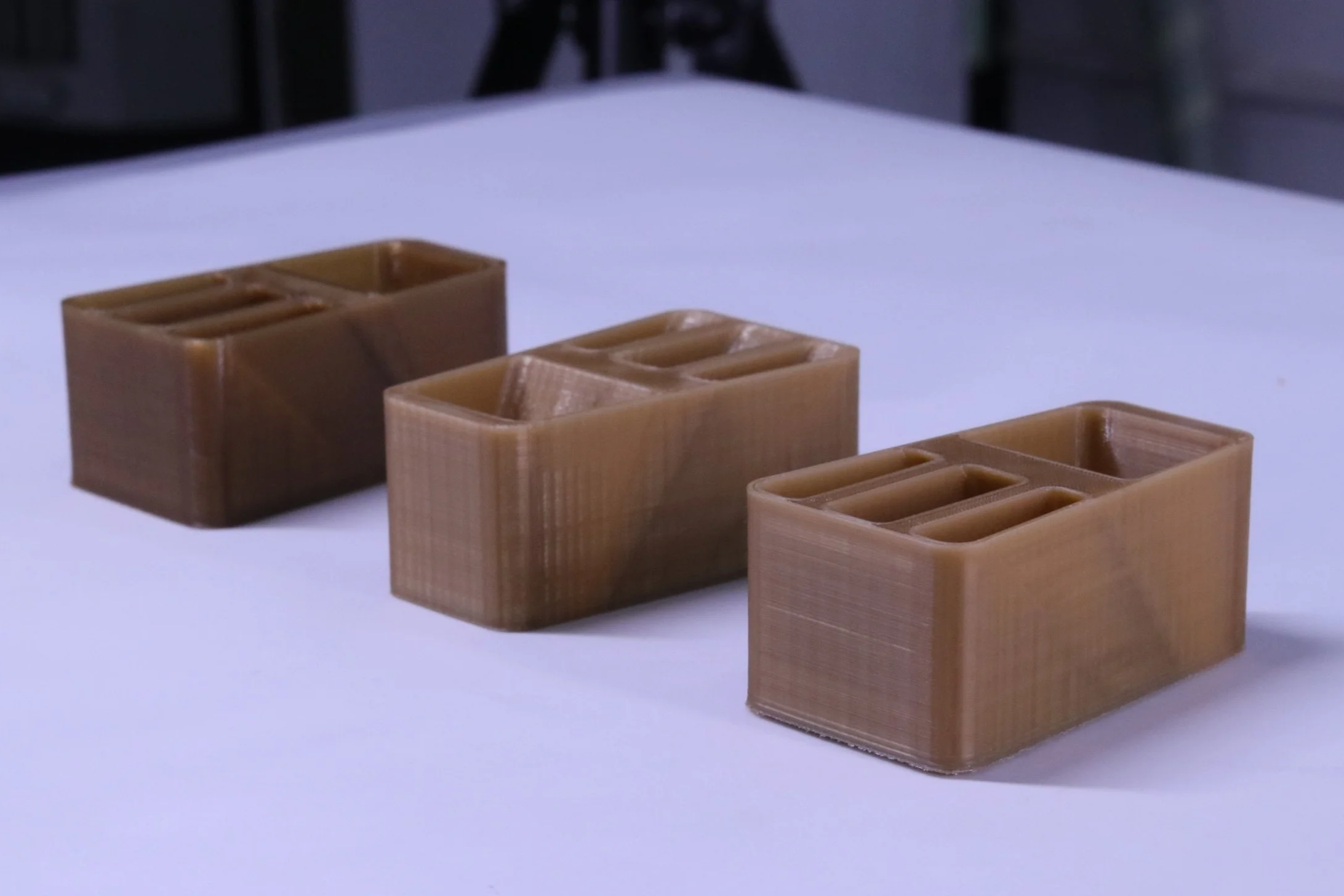 Three small wooden containers with multiple compartments are placed on a white surface, with a blurred background.