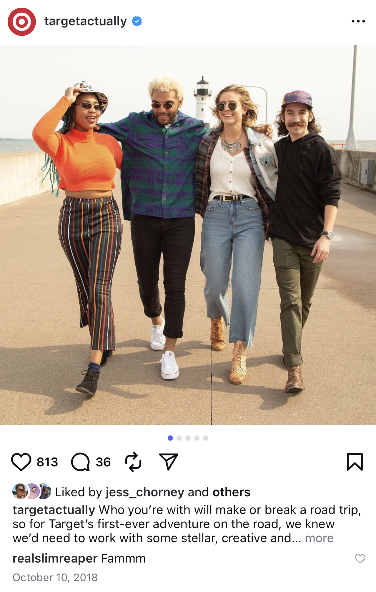 Four diverse friends walk arm-in-arm along a road near the coast, with a lighthouse in the background. They are smiling and dressed casually.