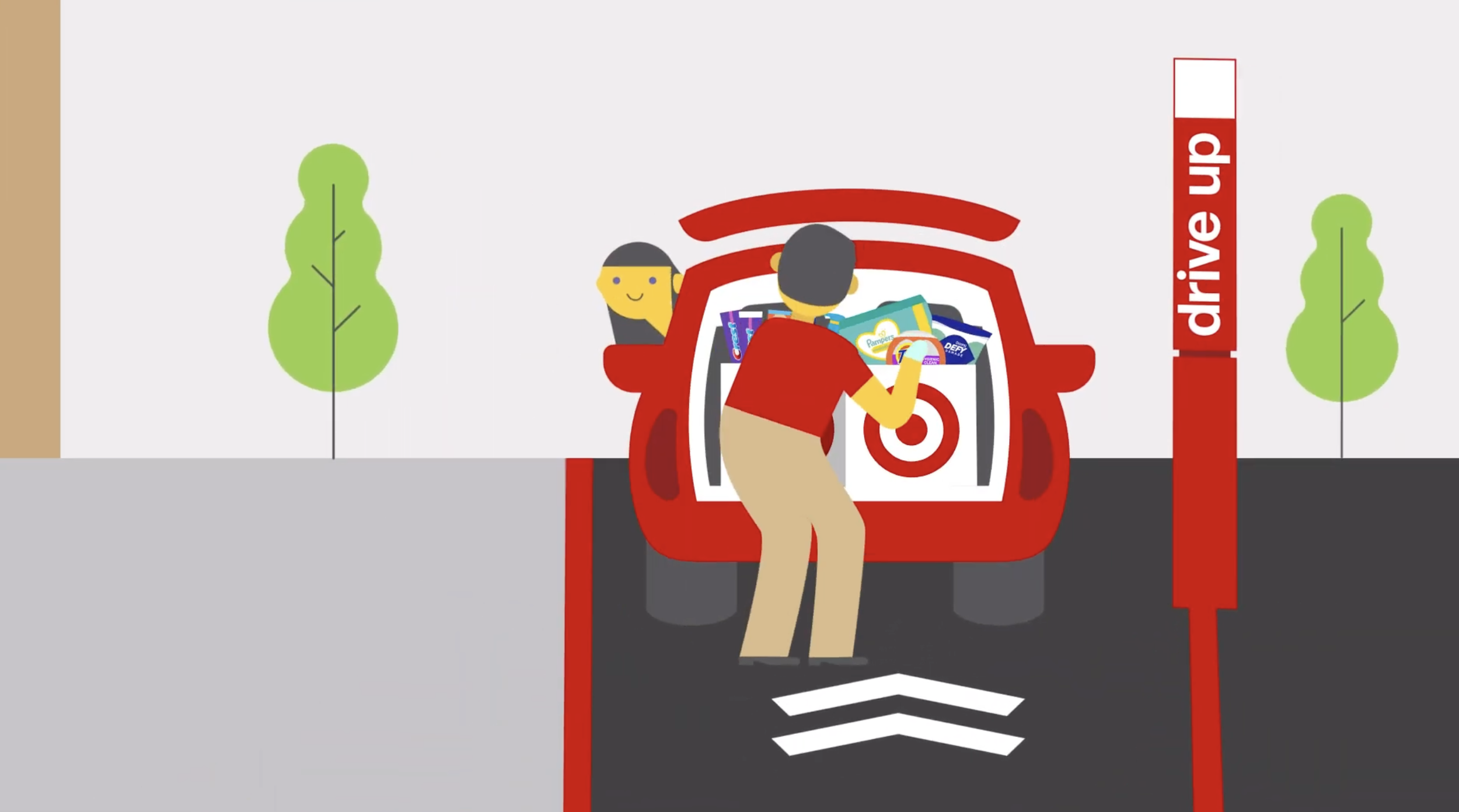 A person loading products into a red car at a drive-up grocery pickup station with a sign that reads 'drive up' and trees in the background.