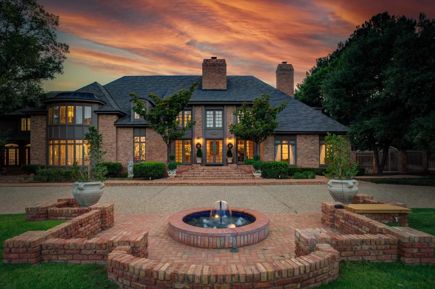 Brick home with a landscaped courtyard at sunset.