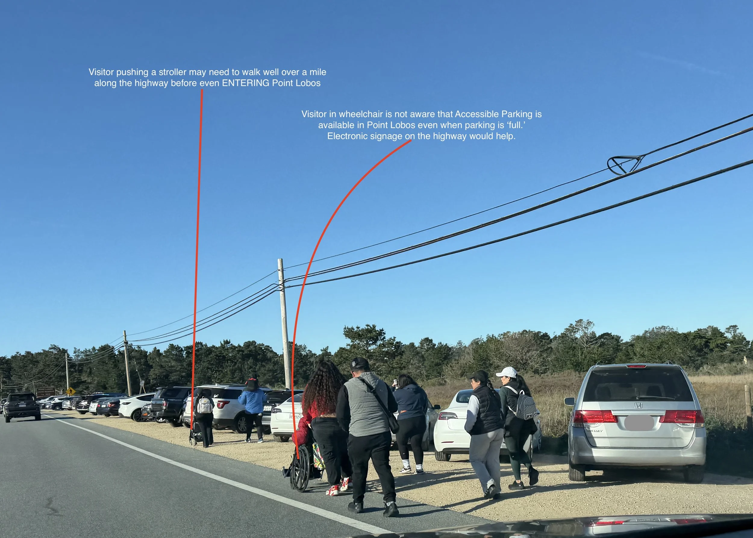 Visitors pushing a stroller, and others pushing someone in a wheelchair make their way along busy Highway 1 to Point Lobos State Natural Reserve.