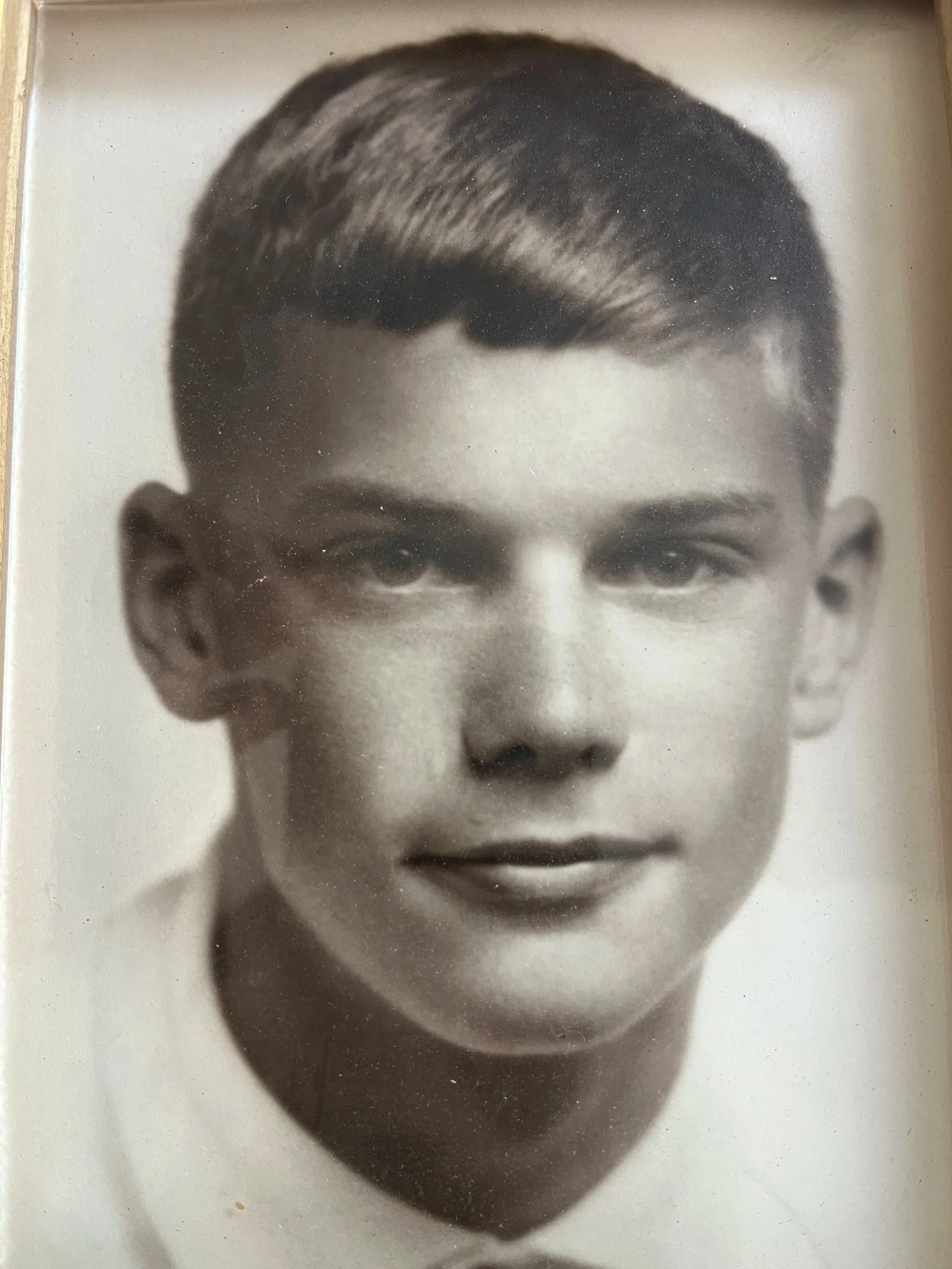 Black and white portrait photo of a young man with short hair, wearing a collared shirt.