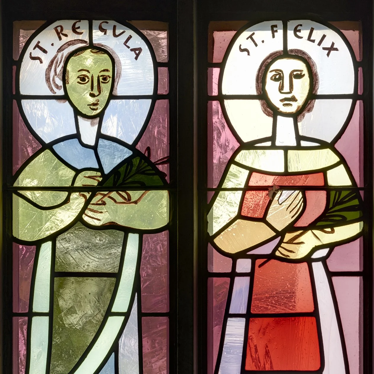Colorful stained glass windows depicting Felix and Regula with hands in prayer, labeled 'St. Felix' and 'St. Regula' at the top.