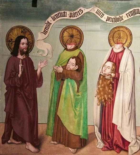 Religious fresco depicting Jesus Christ on the left with a halo, and two saints on the right with halos, holding severed heads. A scroll with Latin text flows above them.