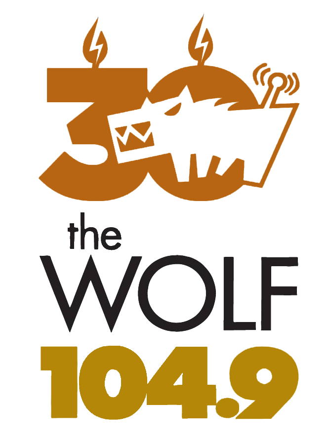 Logo for radio station 104.9 the Wolf featuring a stylized wolf's face, a lightning bolt, a radio antenna, and electrical sparks in black and gold colors.