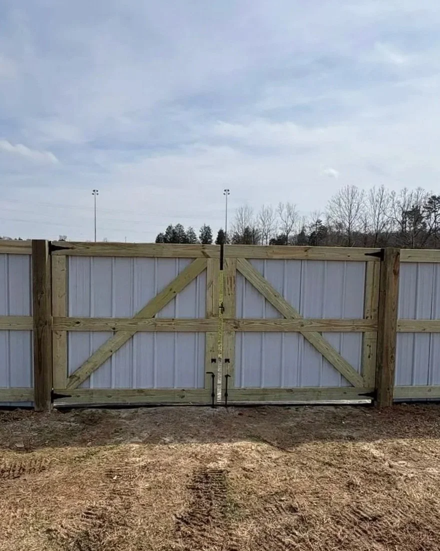 Custom corrugated metal and treated wood frame privacy fence featuring a heavy-duty double drive gate with diagonal bracing, installed by Lane's Fence.