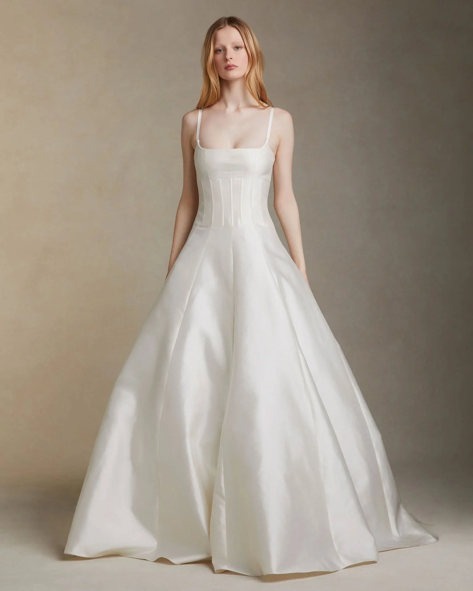Model wearing a Danielle Frankel A-line wedding dress featuring a structured bodice with thin straps, visible boning details, and a smooth, elegant satin skirt.