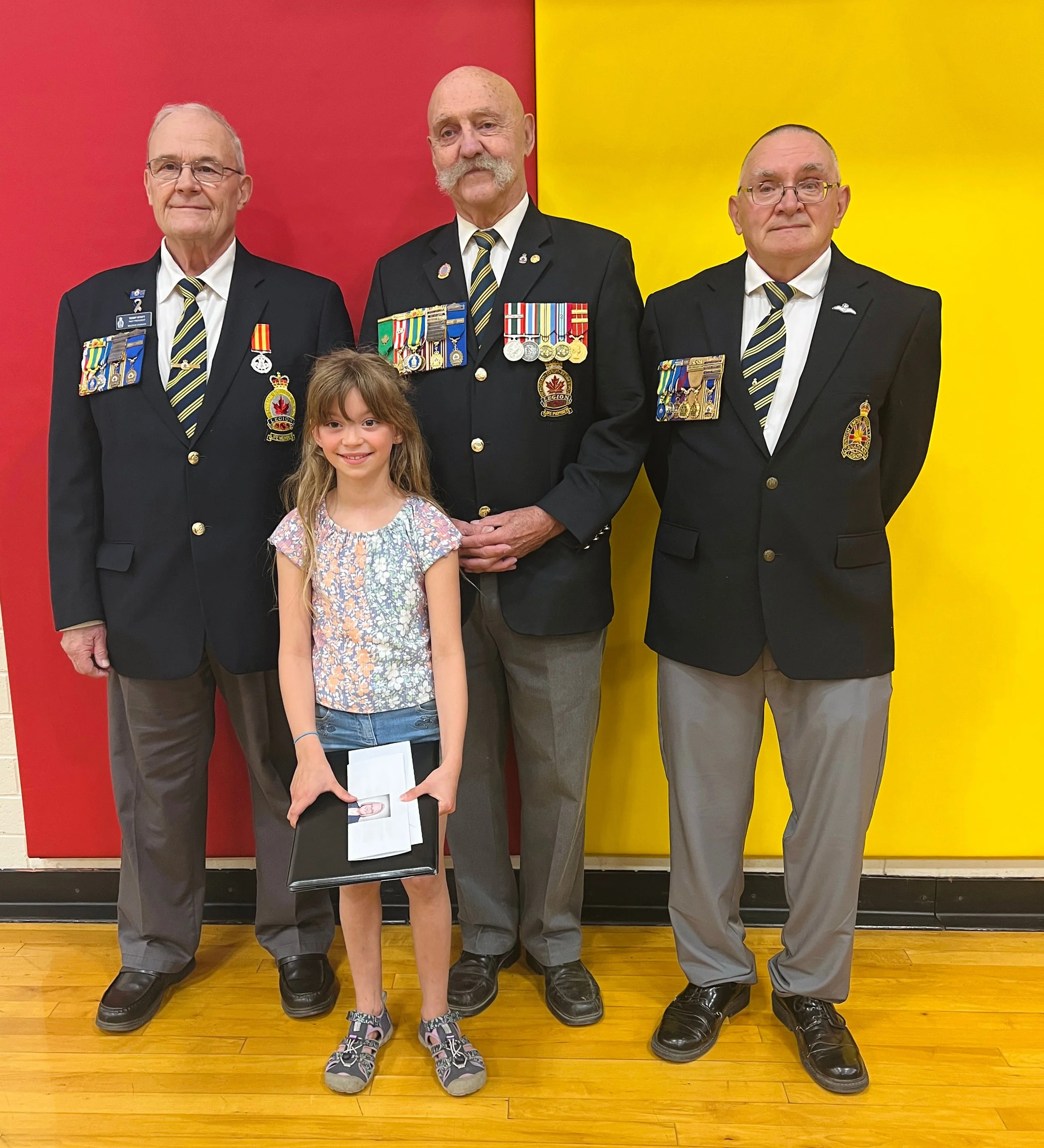 Young girls standing with 3 Canadian Veterans with art award