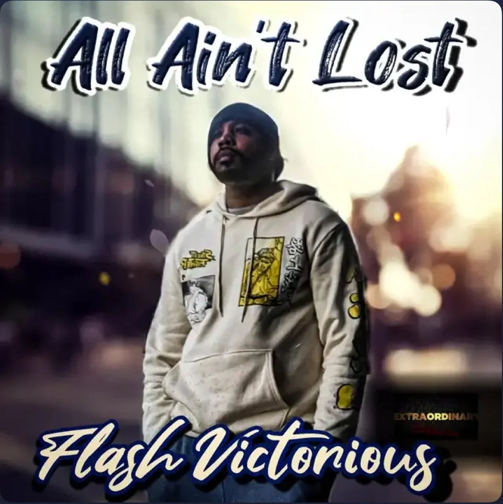 A man wearing a gray hoodie with graphic patches stands outdoors during sunset, with blurred city lights in the background. Text overlay says 'All Ain't Lost' at the top and 'Flash Victorious' at the bottom.