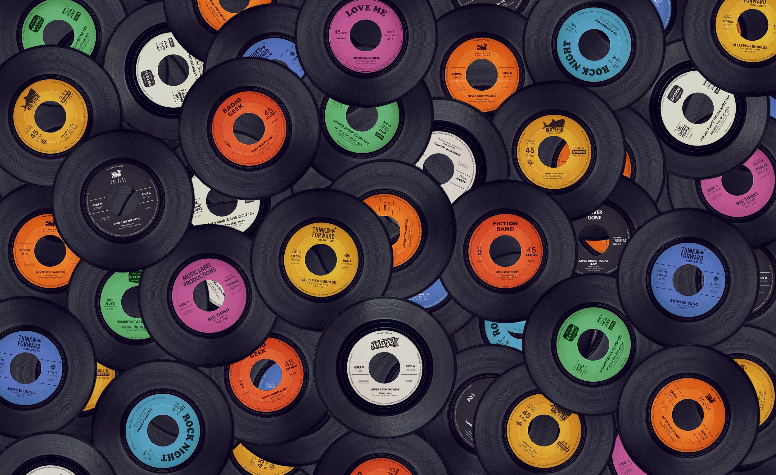 A large collection of vinyl records with colorful labels featuring various songs and artists, arranged in a dense, overlapping pattern.