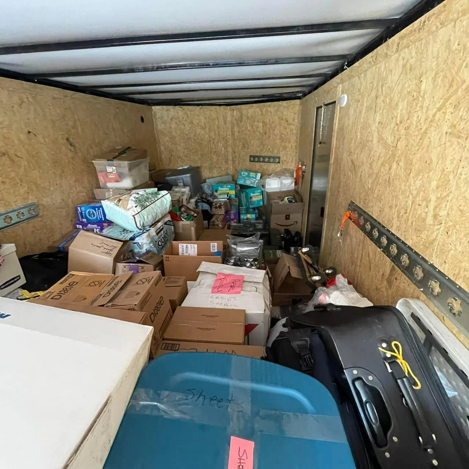 Inside of a storage unit filled with boxes, bags, and miscellaneous items.