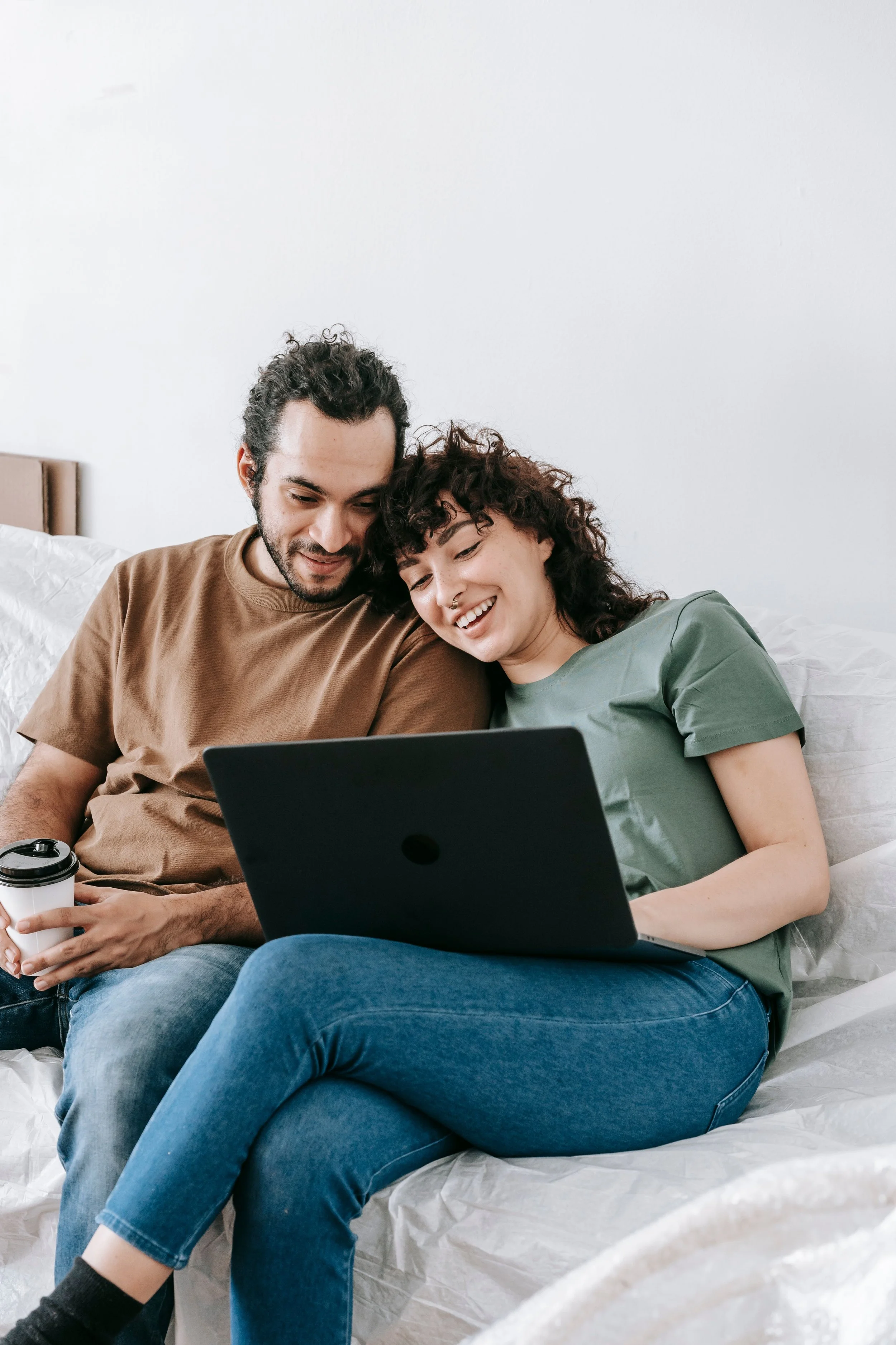 Couple sitting together on a couch with a laptop, representing a virtual couples therapy session