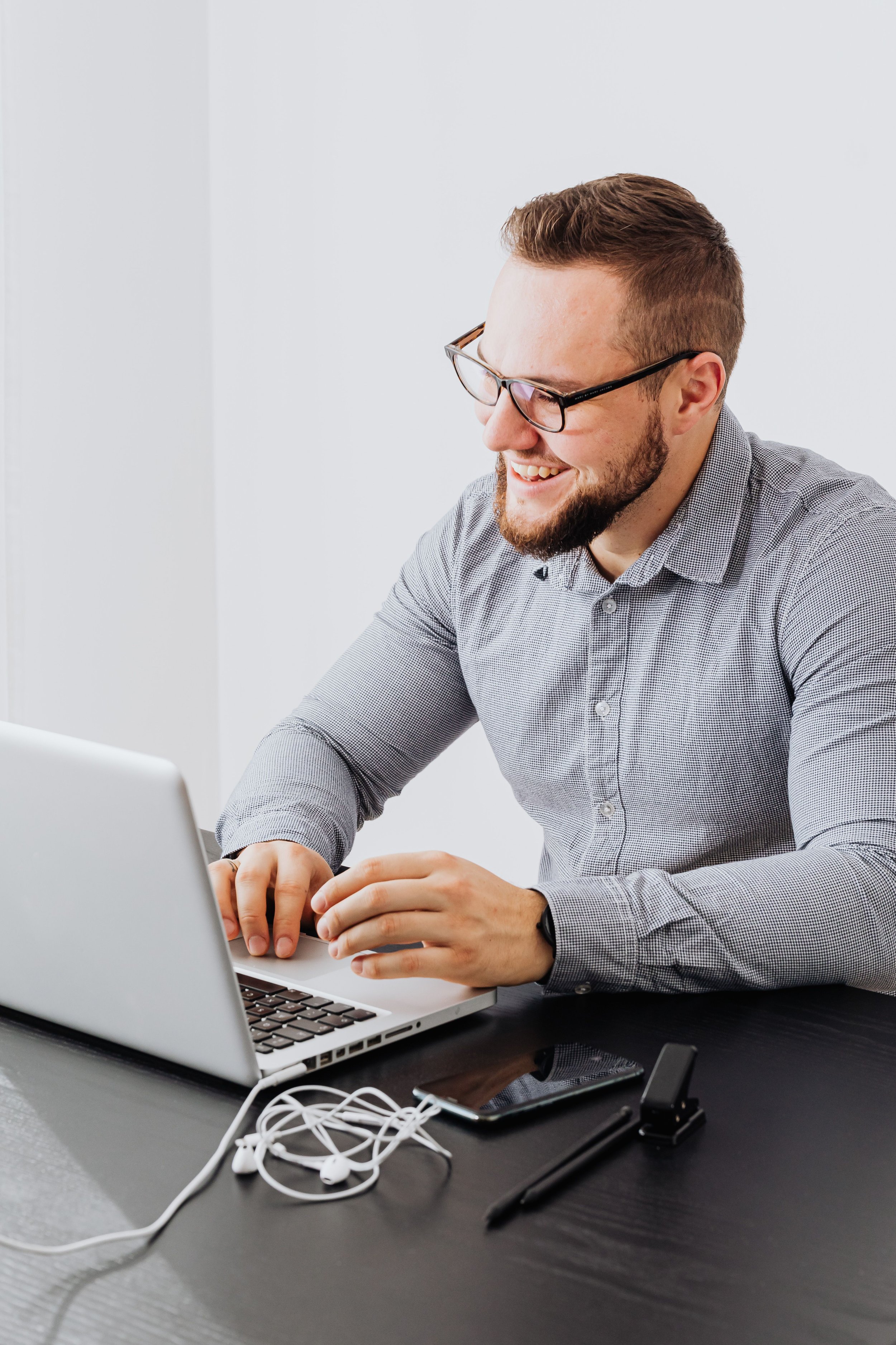 Man smiling while working on a laptop, representing a virtual individual therapy session