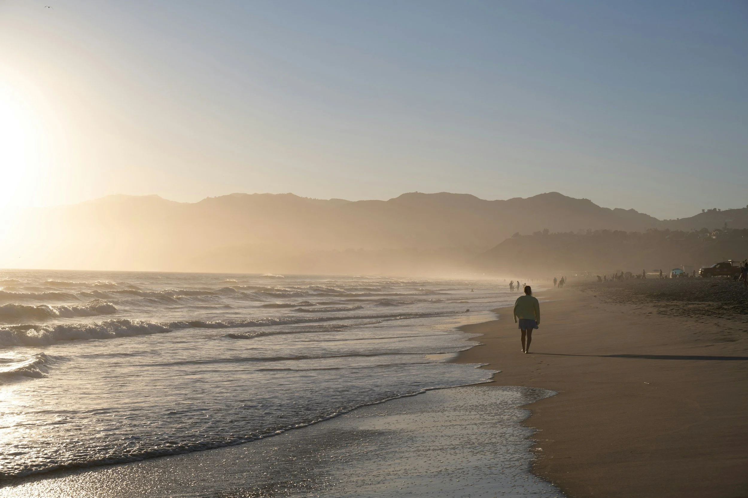 Person walking alone on a beach at sunrise, representing finding calm while managing anxiety and depression