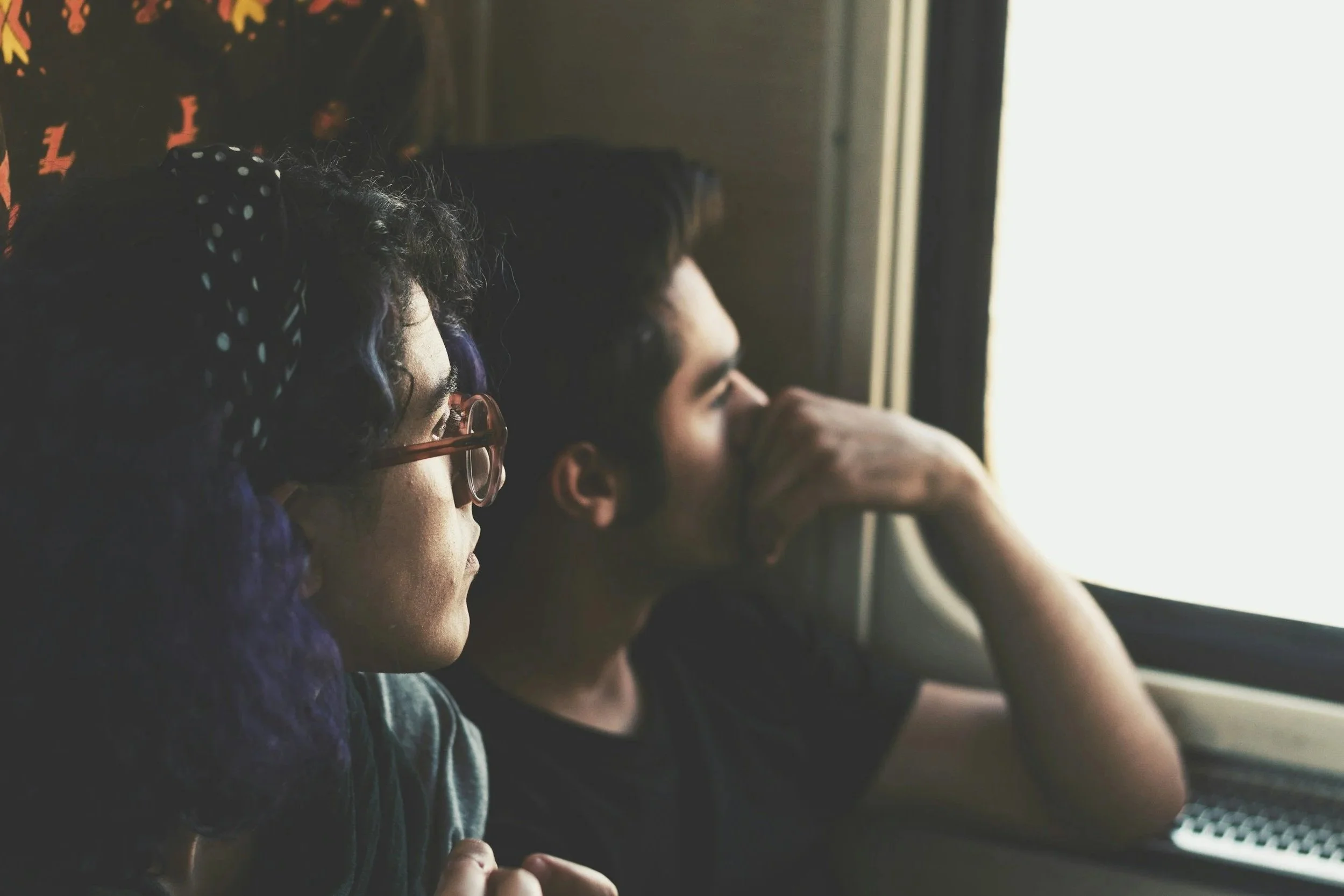 Couple sitting closely together looking out a window, reflecting on communication and repair in their relationship