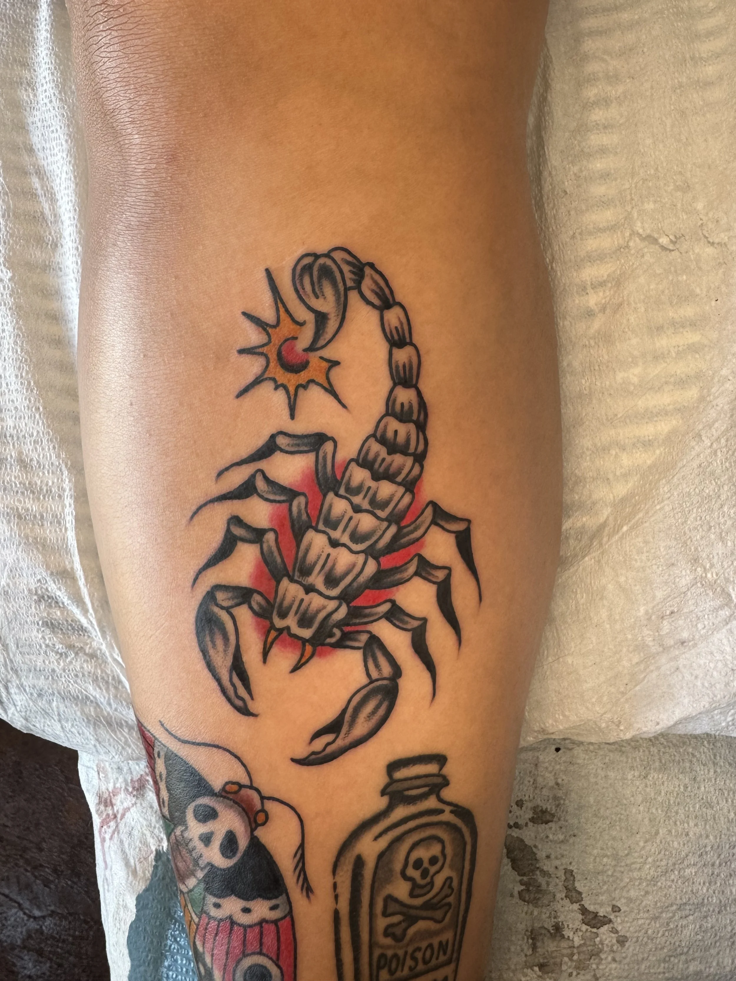 Tattoo of a scorpion with a skull and crossbones with the word 'POISON' on the leg.