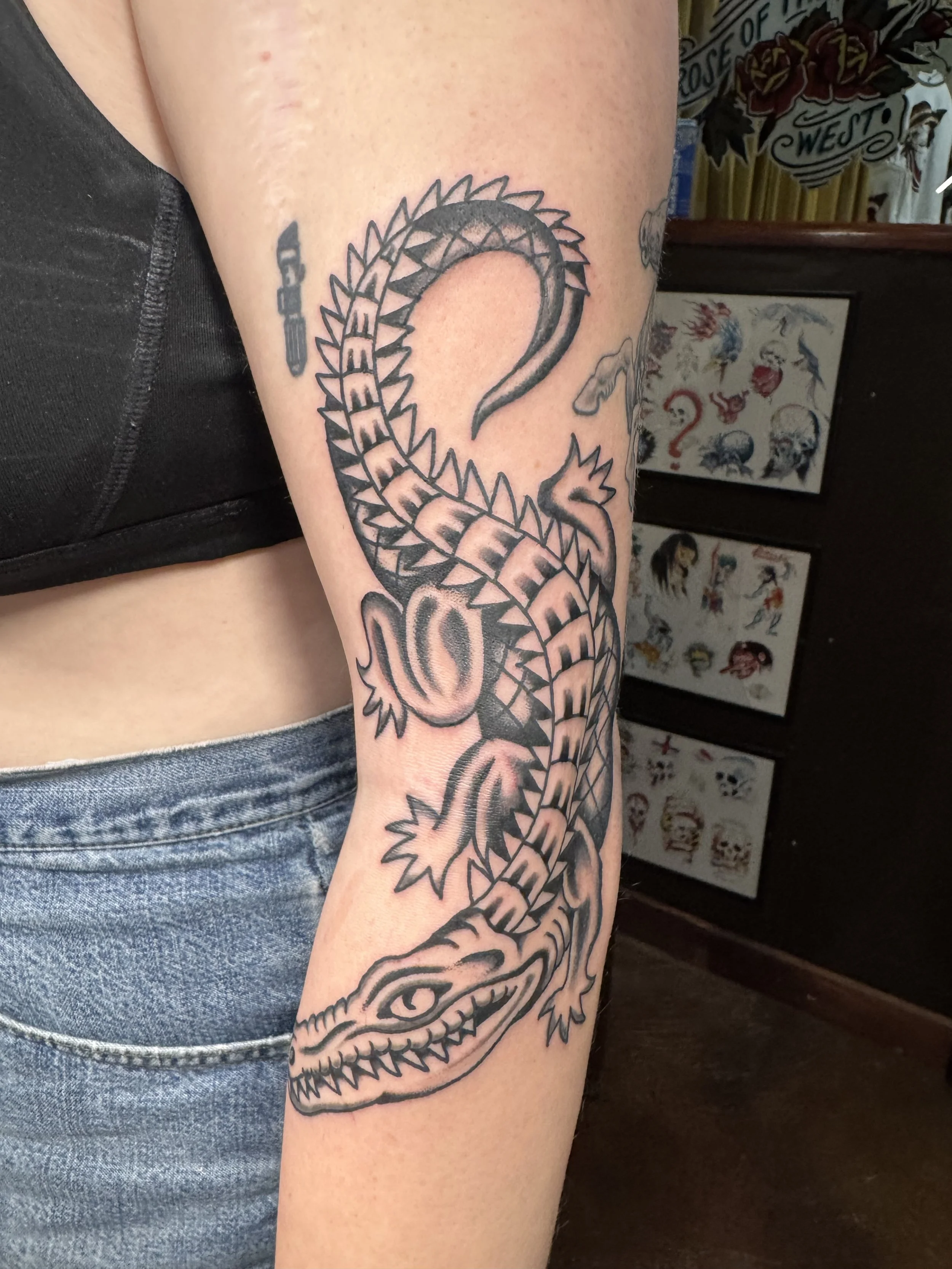 Tattoo of a snake with the word "SNAKE" on the person's upper arm.
