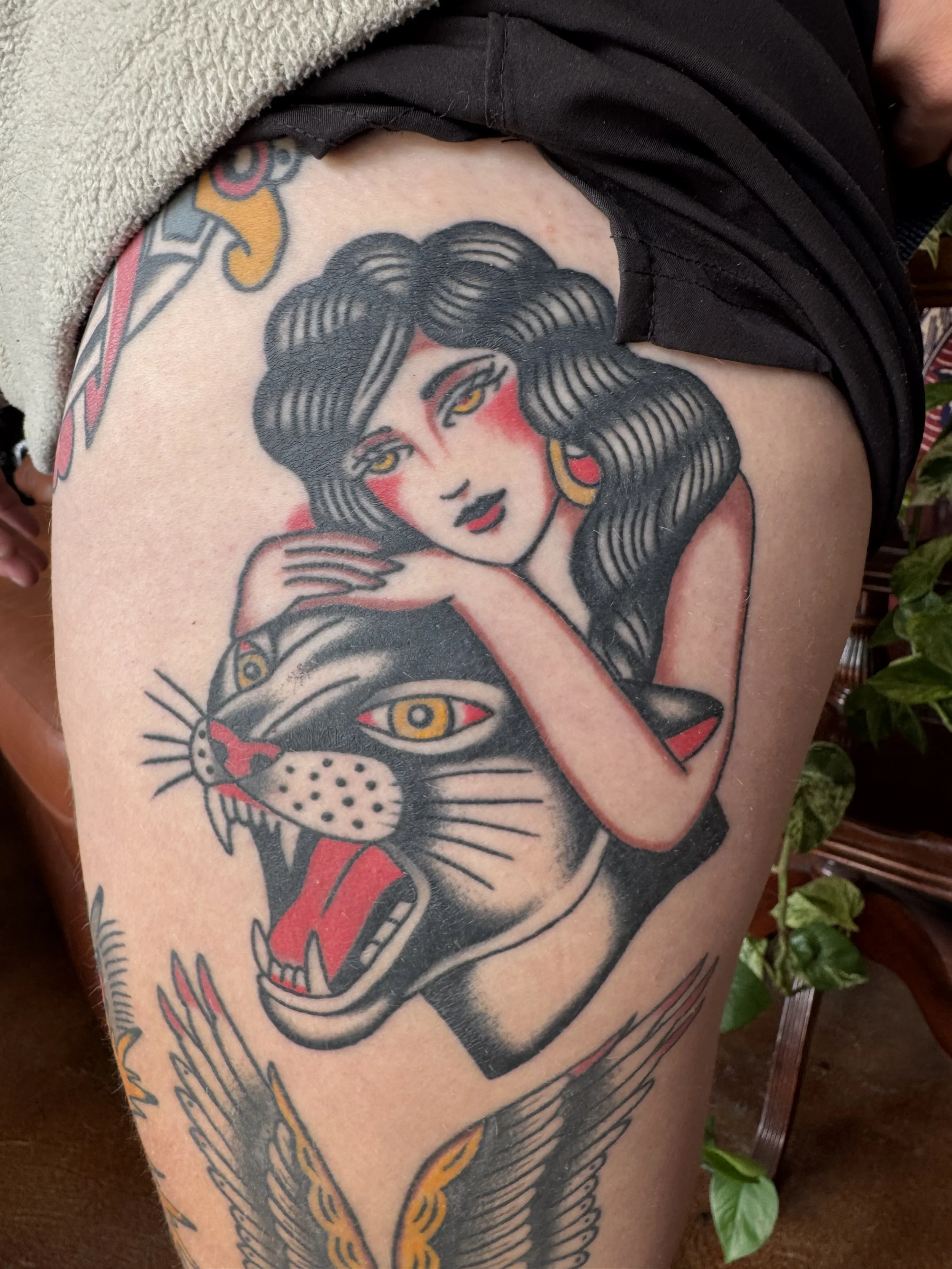Tattoo of a woman's face with long hair, surrounded by eyes and animal elements, on a person's arm.