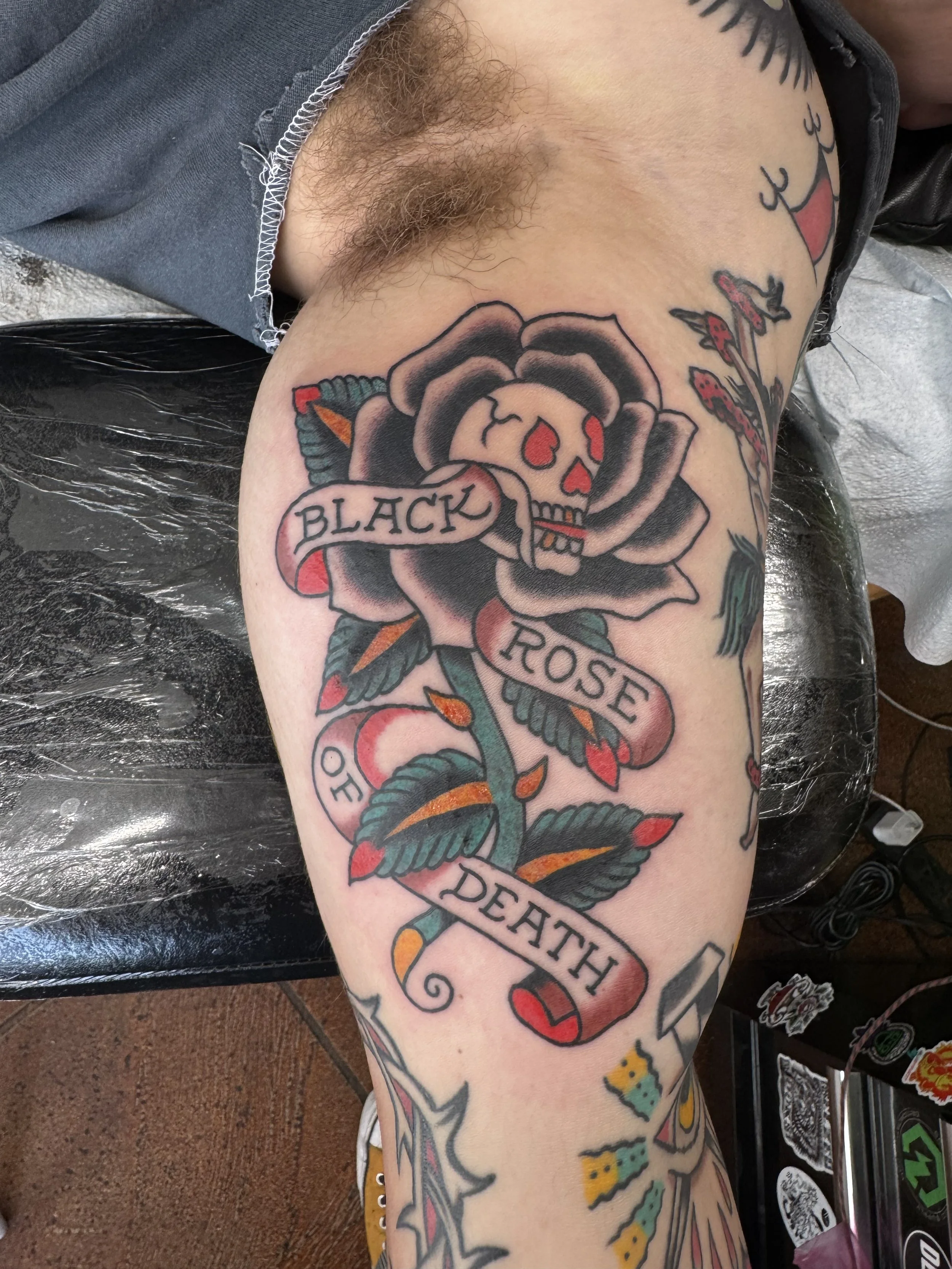 Tattoo of a rose with a banner that reads 'Black Rose' on a person's upper arm.