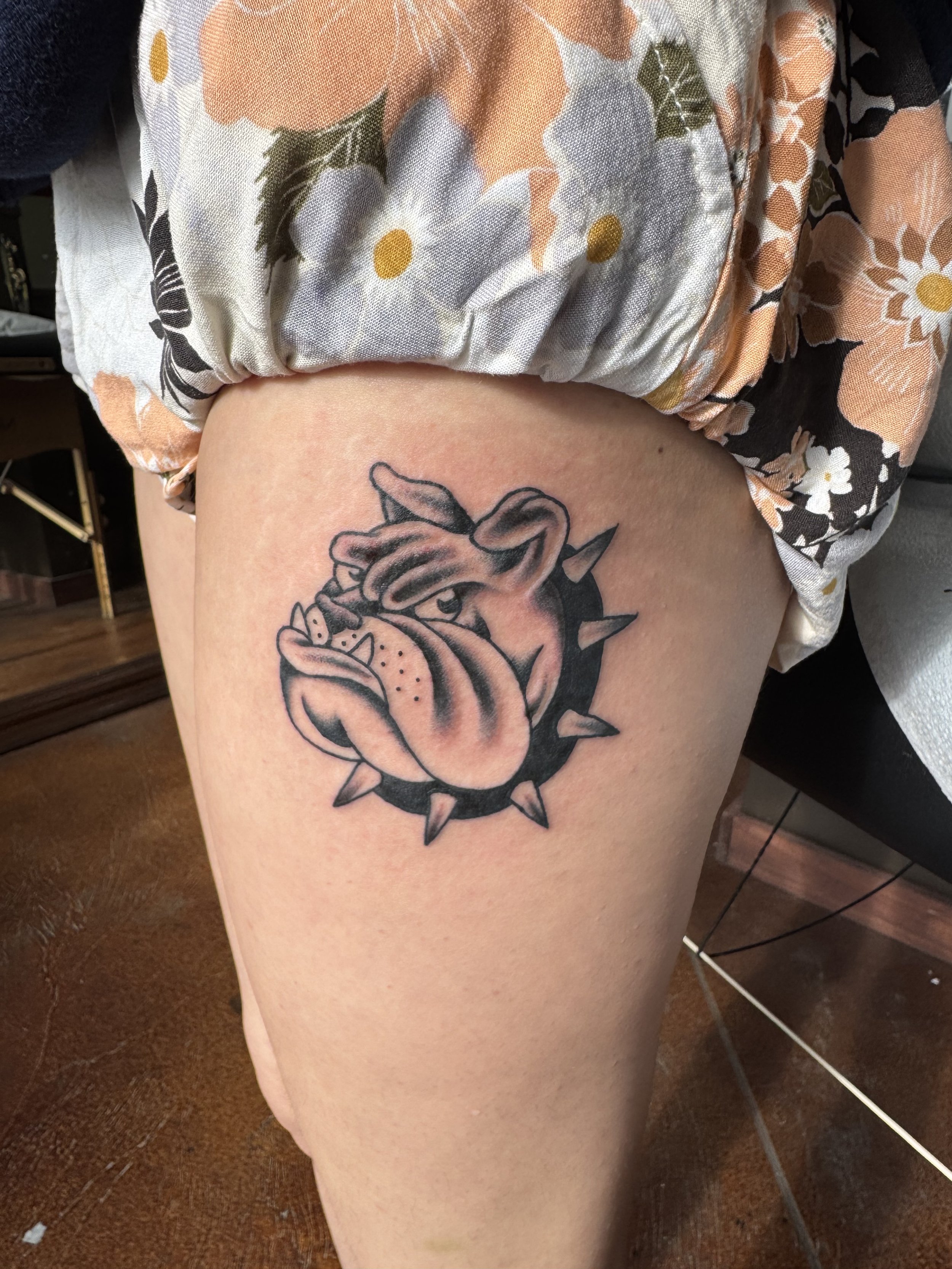 Tattoo of a heart with spikes and a rose, on a person's thigh.