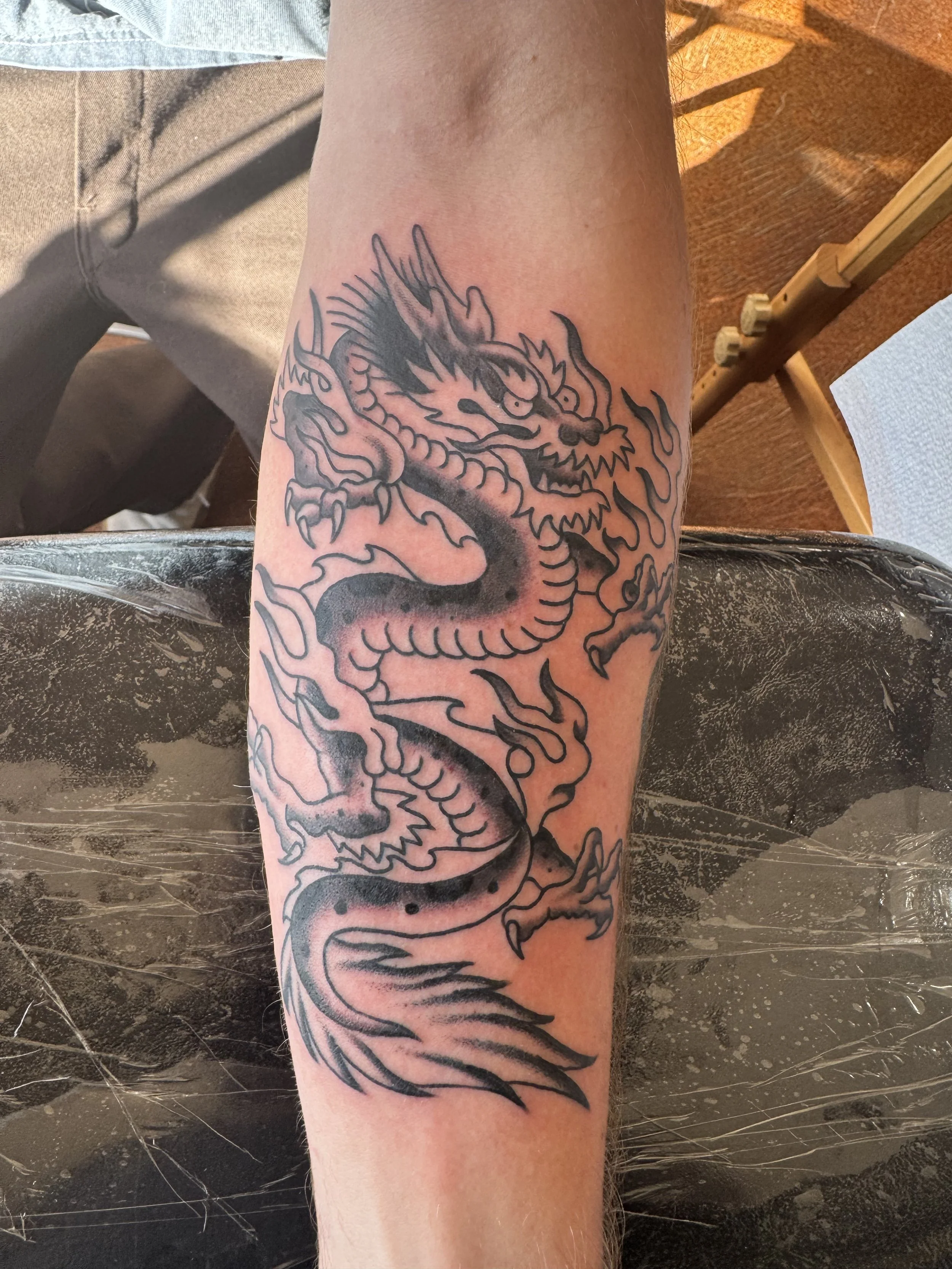 Tattoo of a traditional style dragon on a person's forearm