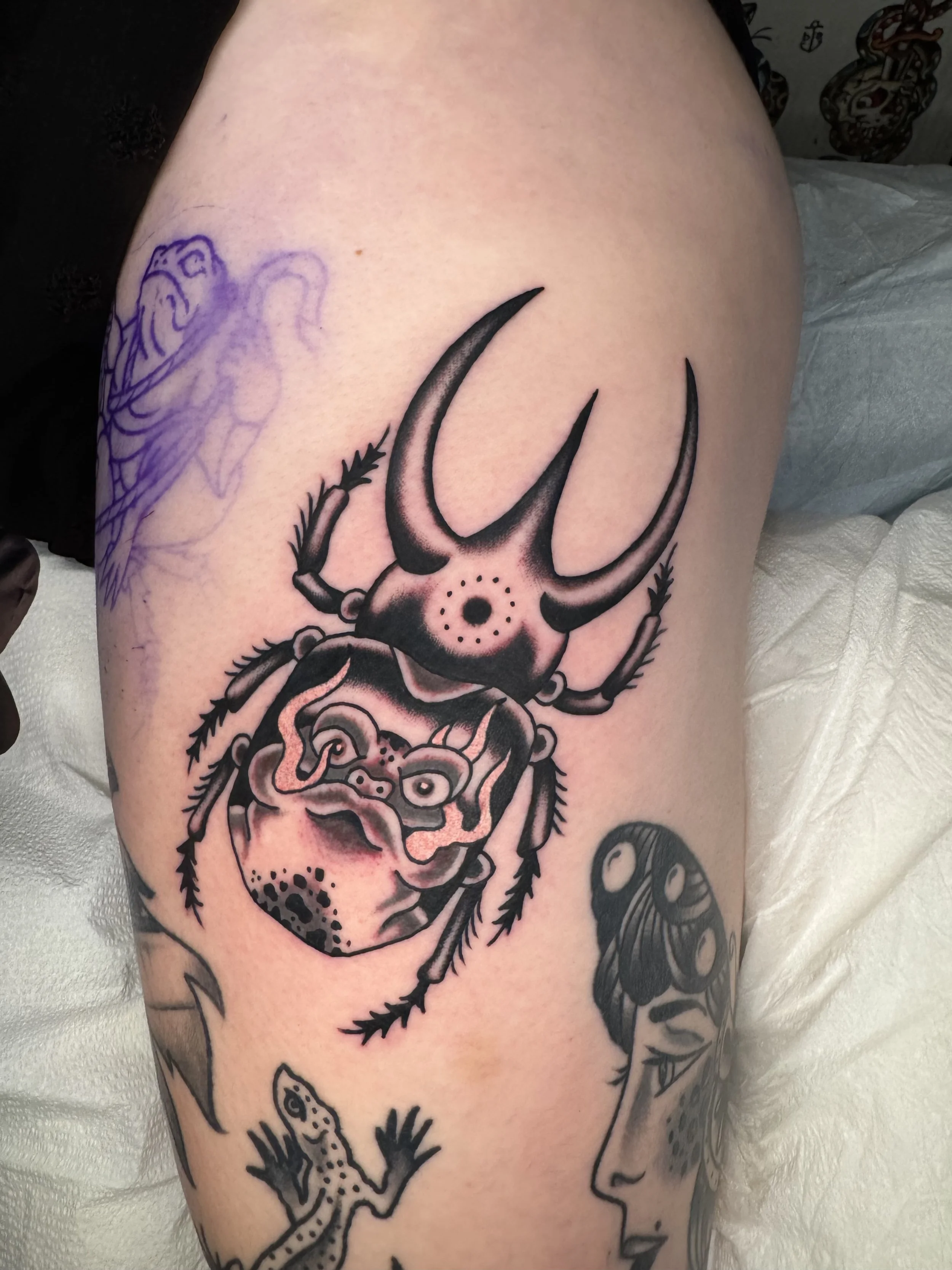 A tattoo of a scorpion on a person's upper arm with a detailed, realistic style, with additional tattoo designs around it.