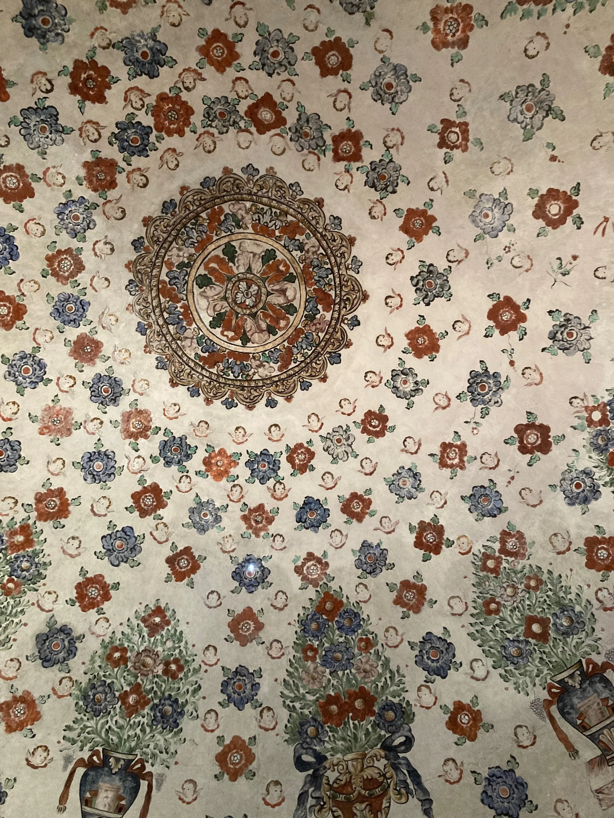 A photo of a painted, domed ceiling. Blue, orange, and red paints in beautiful concentric designs .