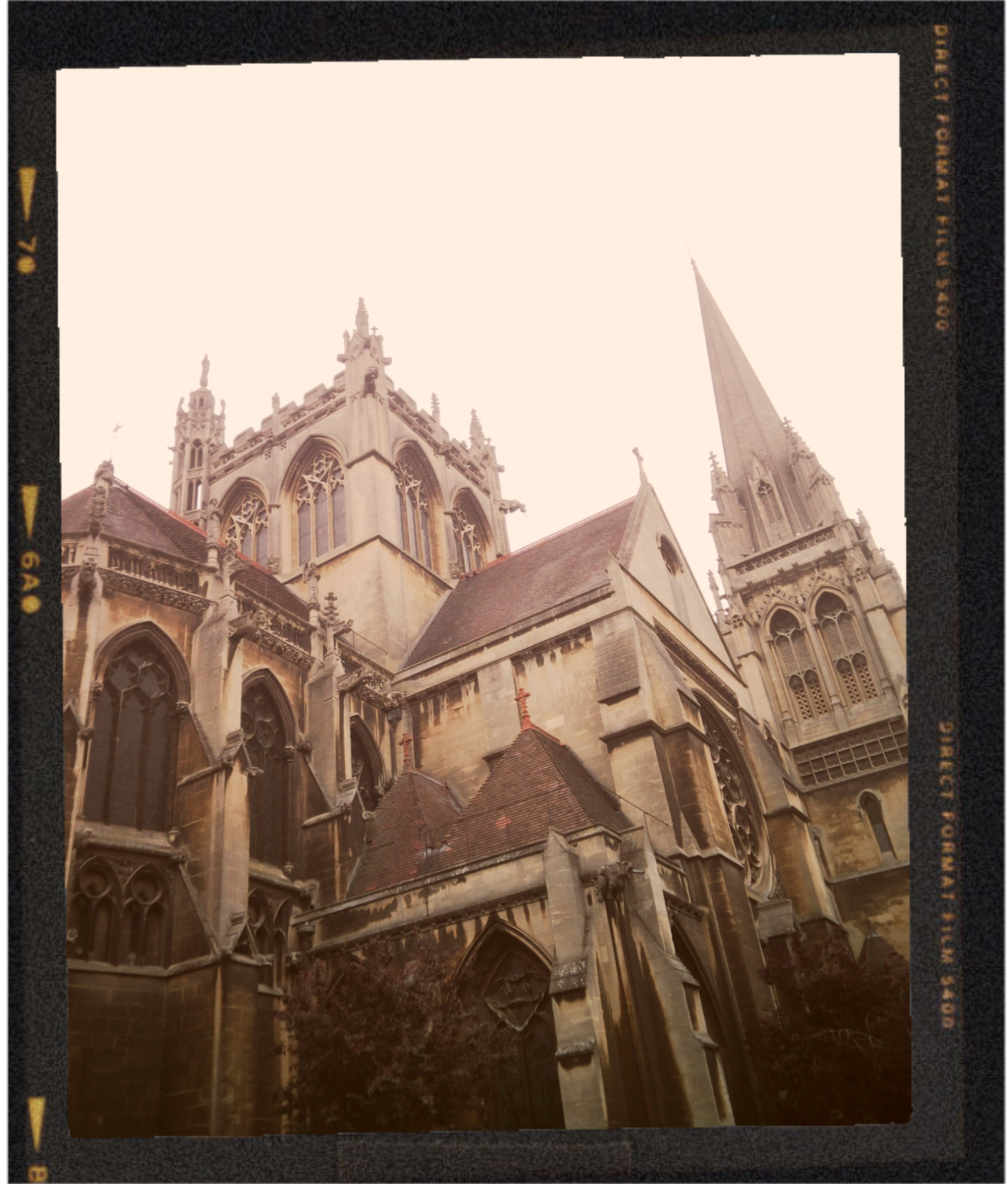 A close-up view of a historic stone church with intricate gothic architecture, including arched windows and spires, under a clear sky.