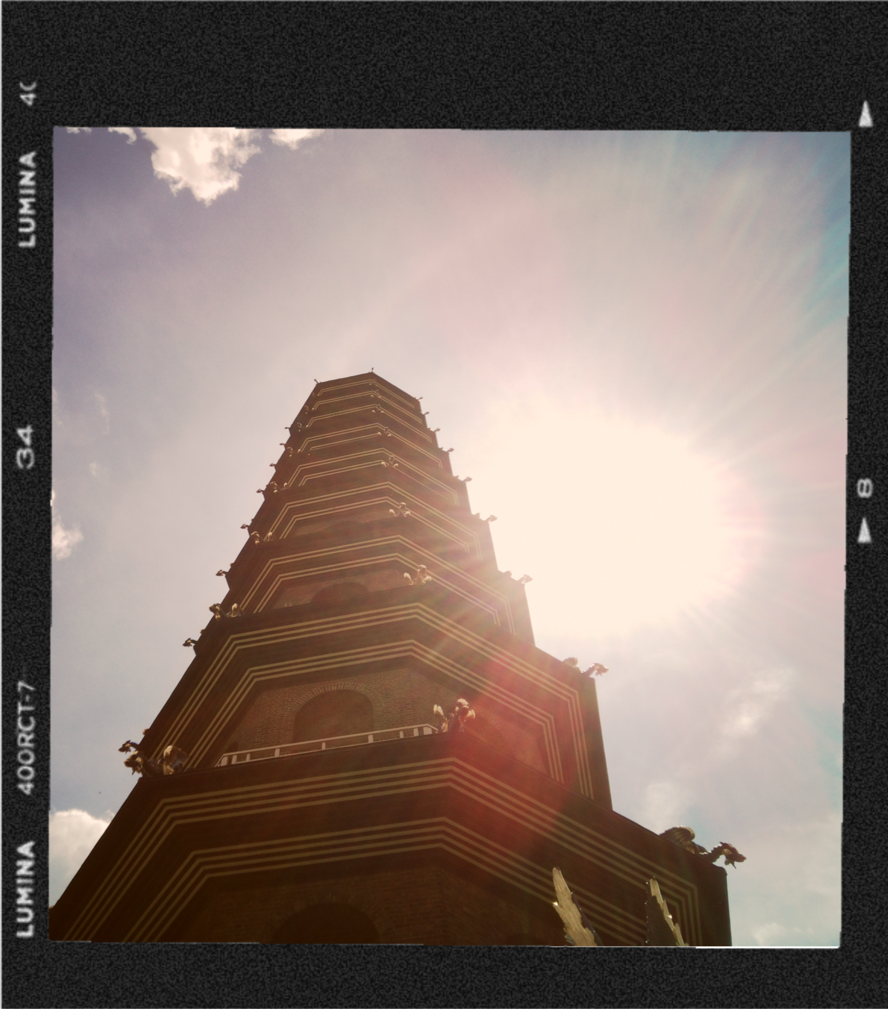 A tall pagoda-style building viewed from below with a partly cloudy sky in the background.
