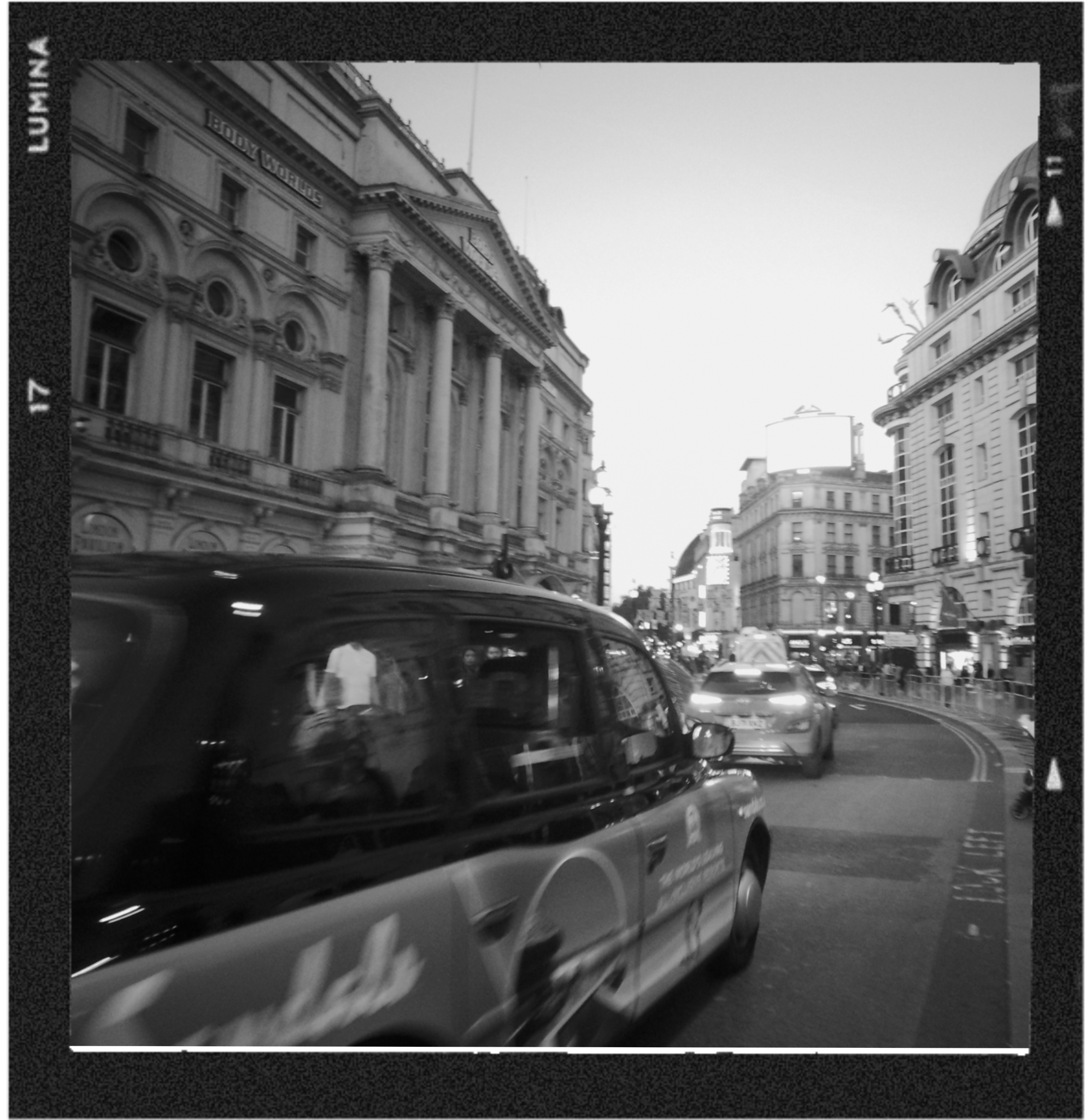 Black and white photo of historic buildings in an urban area, with cars on the street.