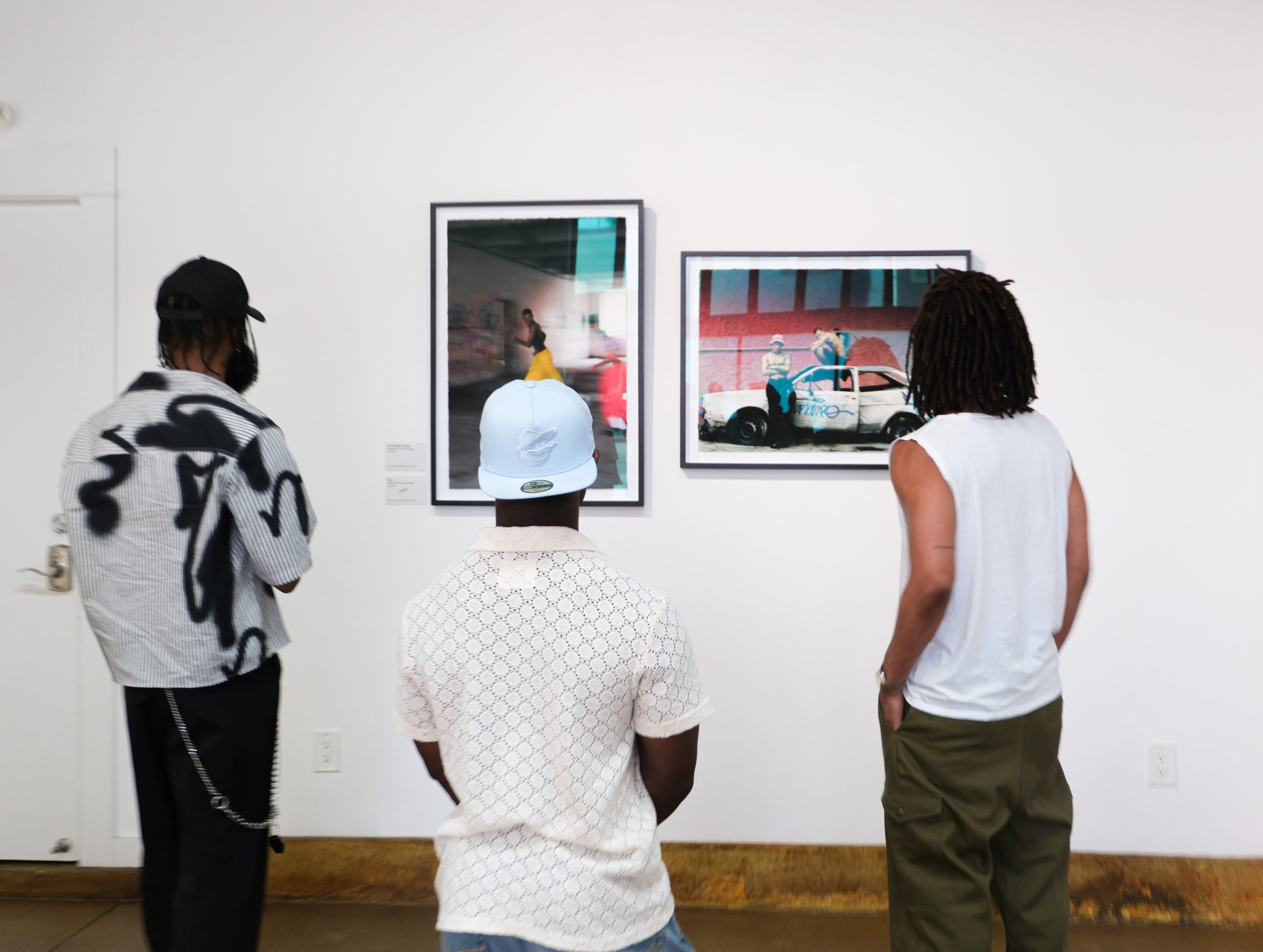 People viewing framed artwork in an art gallery or museum.