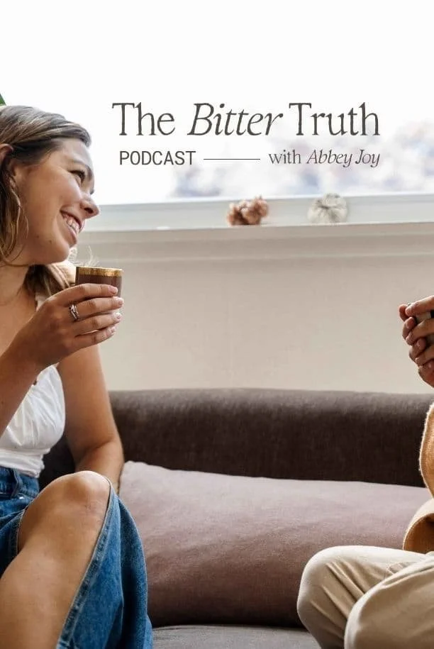 A woman smiling and holding a mug while talking to a person off-camera, with a podcast title 'The Bitter Truth' and host 'Abbey Joy' in the background.